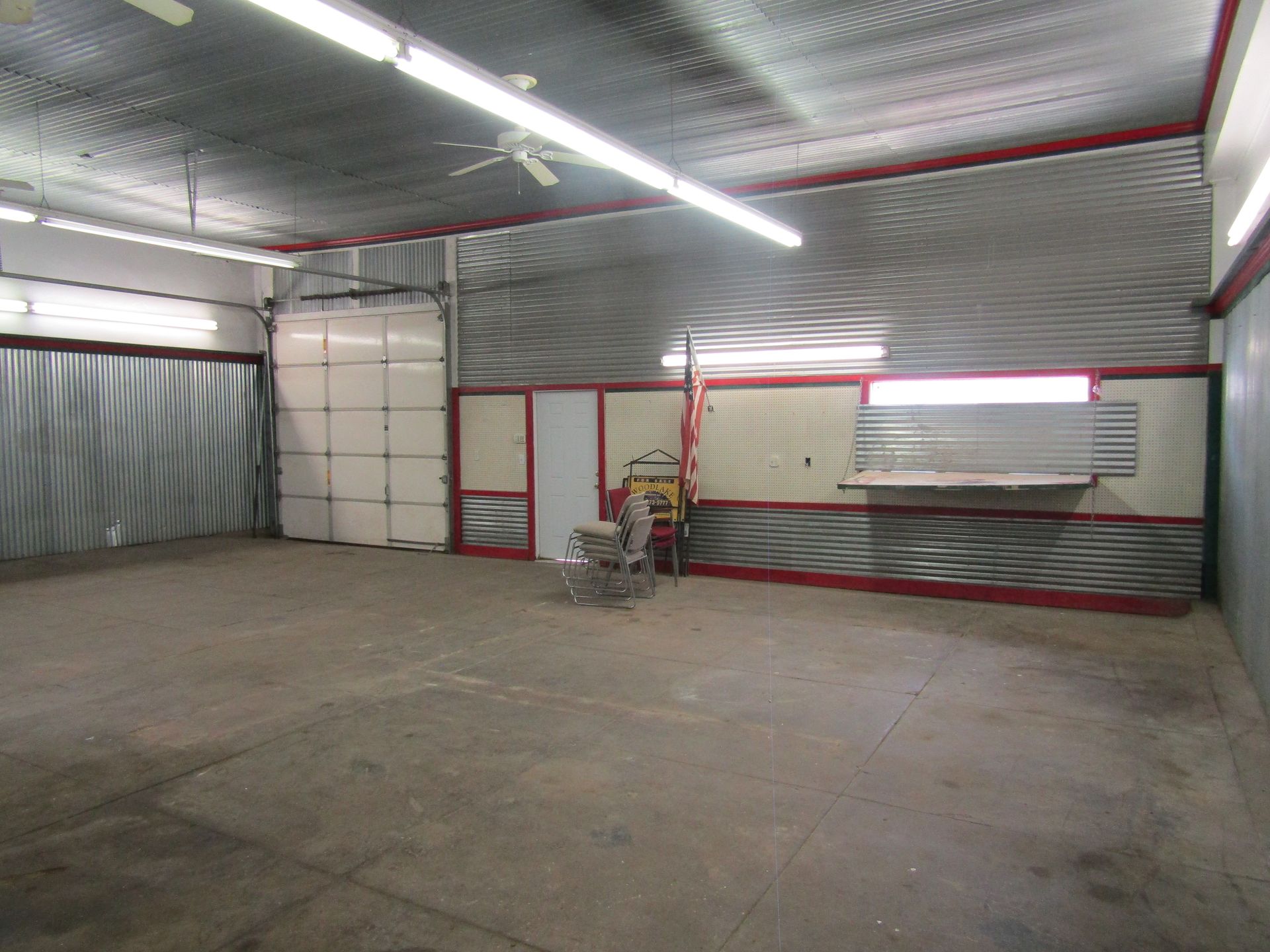 A large empty garage with a ceiling fan and a door.