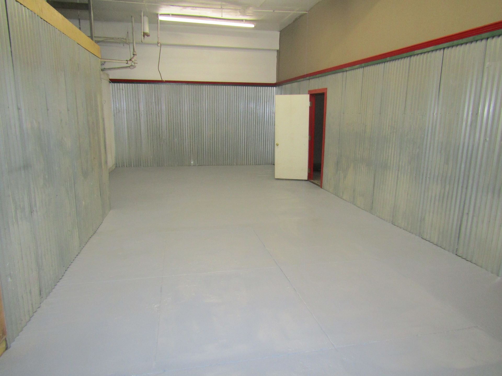 An empty room with a metal wall and a door