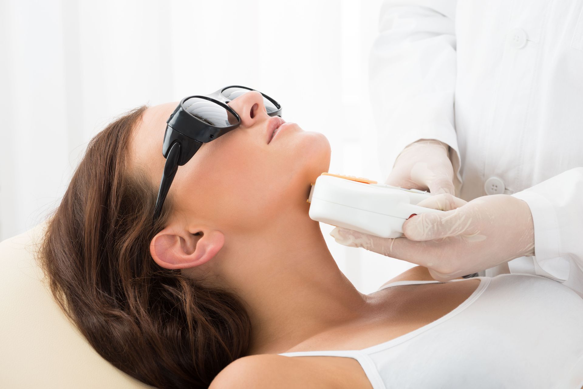 Person receiving laser hair removal treatment on their neck, wearing eye protection.