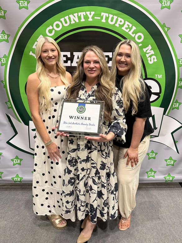 Three women posing with an award plaque