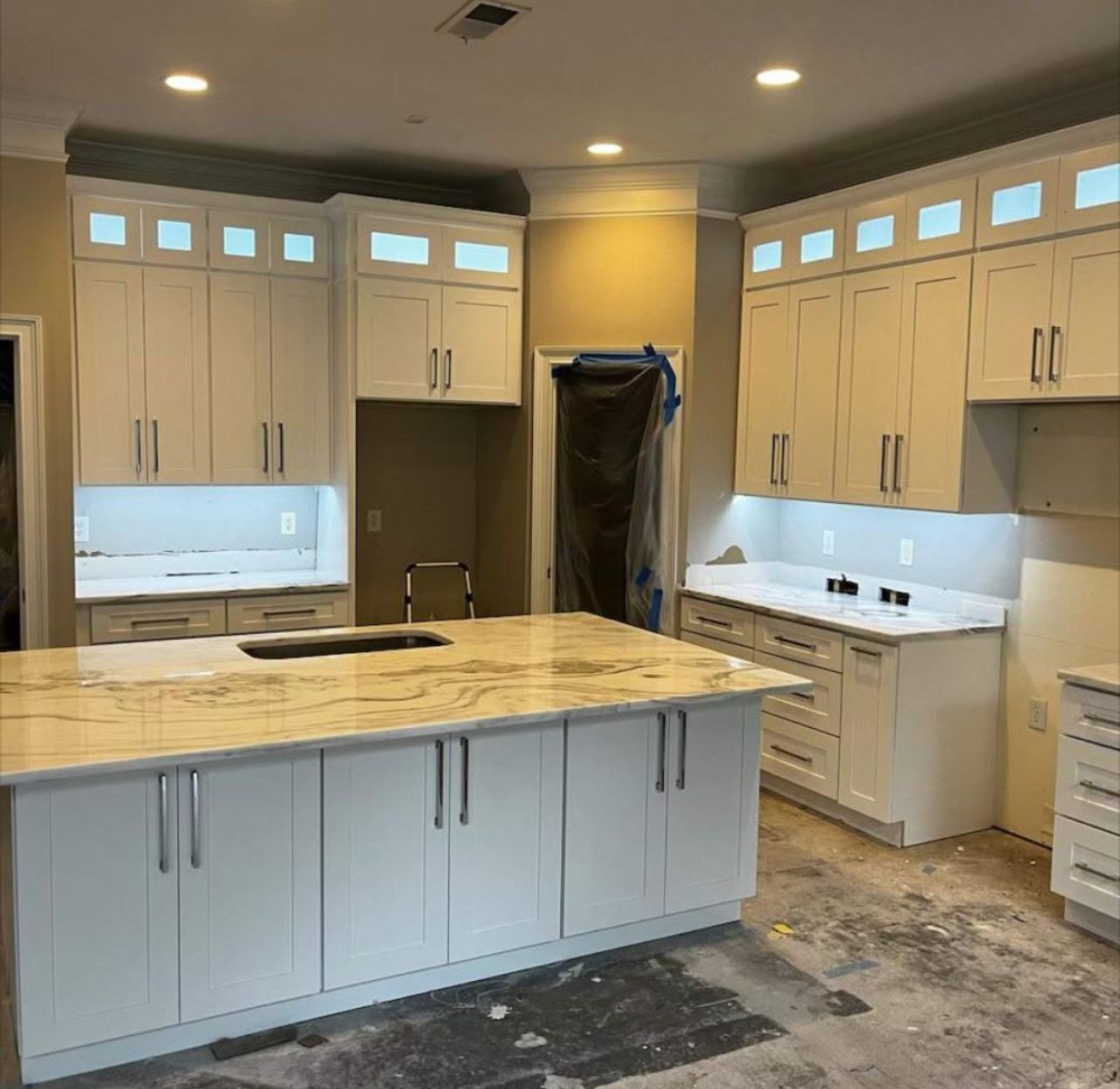A kitchen with white cabinets and a large island in the middle.