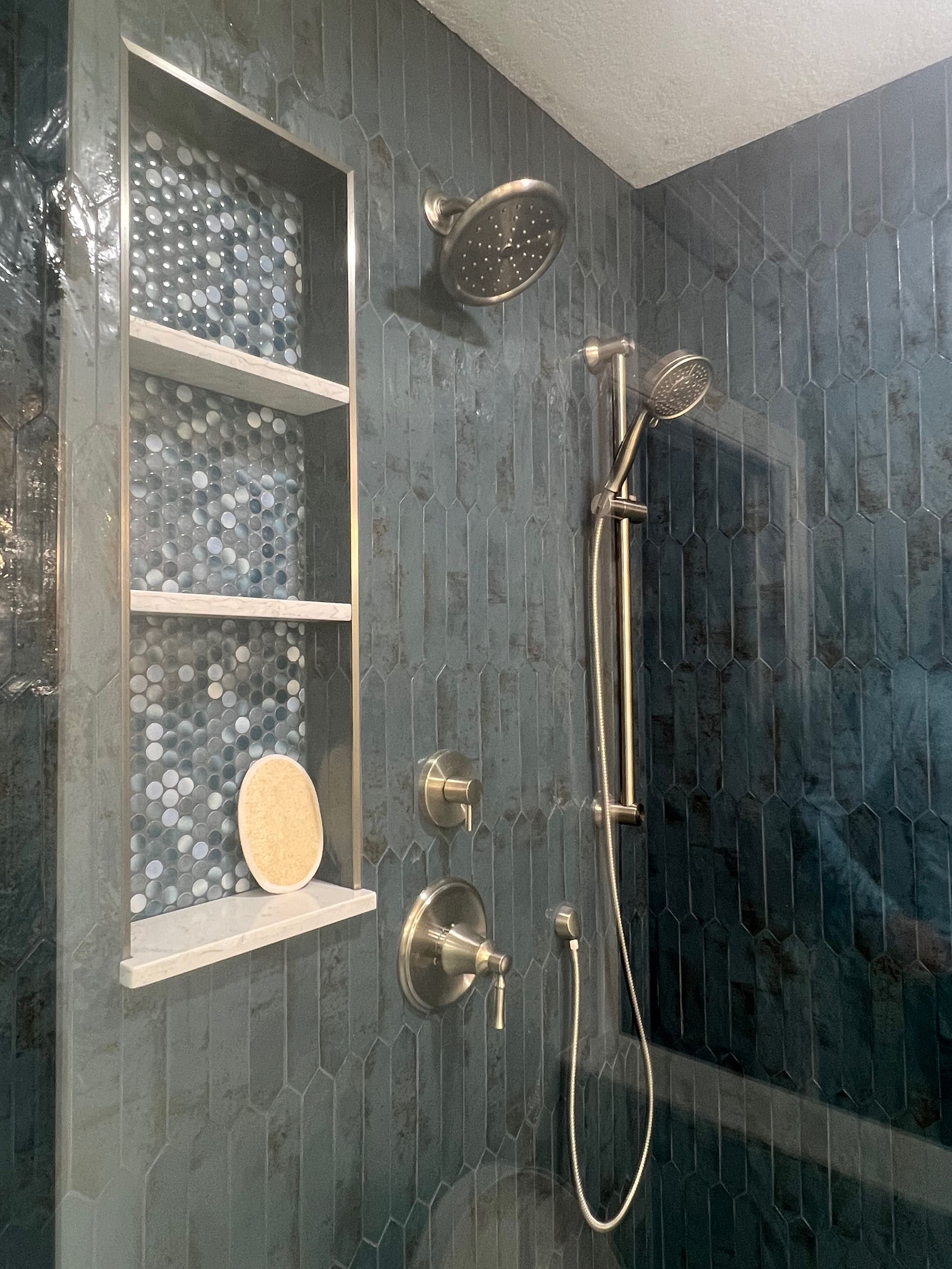 A bathroom with a shower head and a shelf.