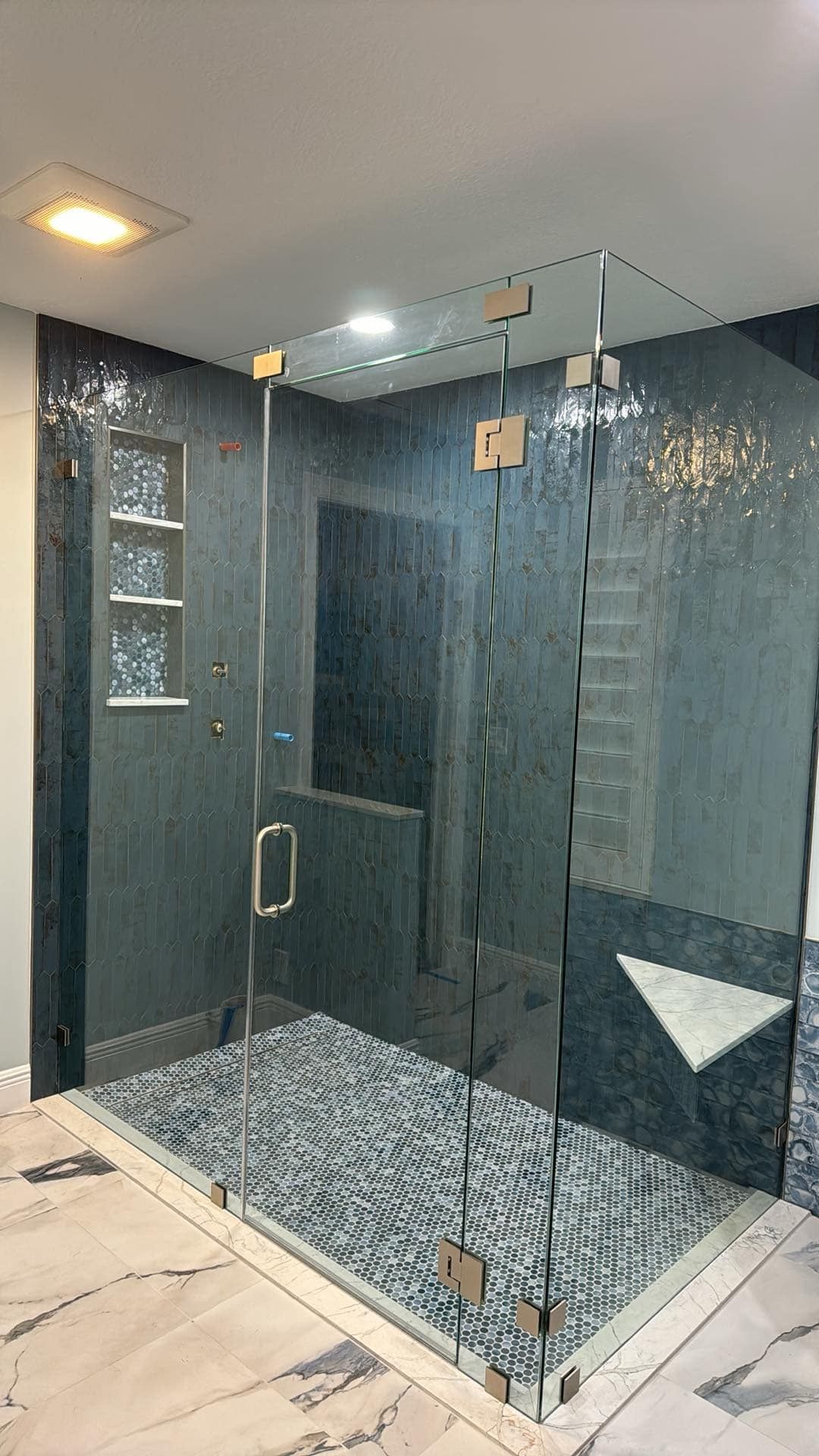 A bathroom with a walk in shower and a glass door.