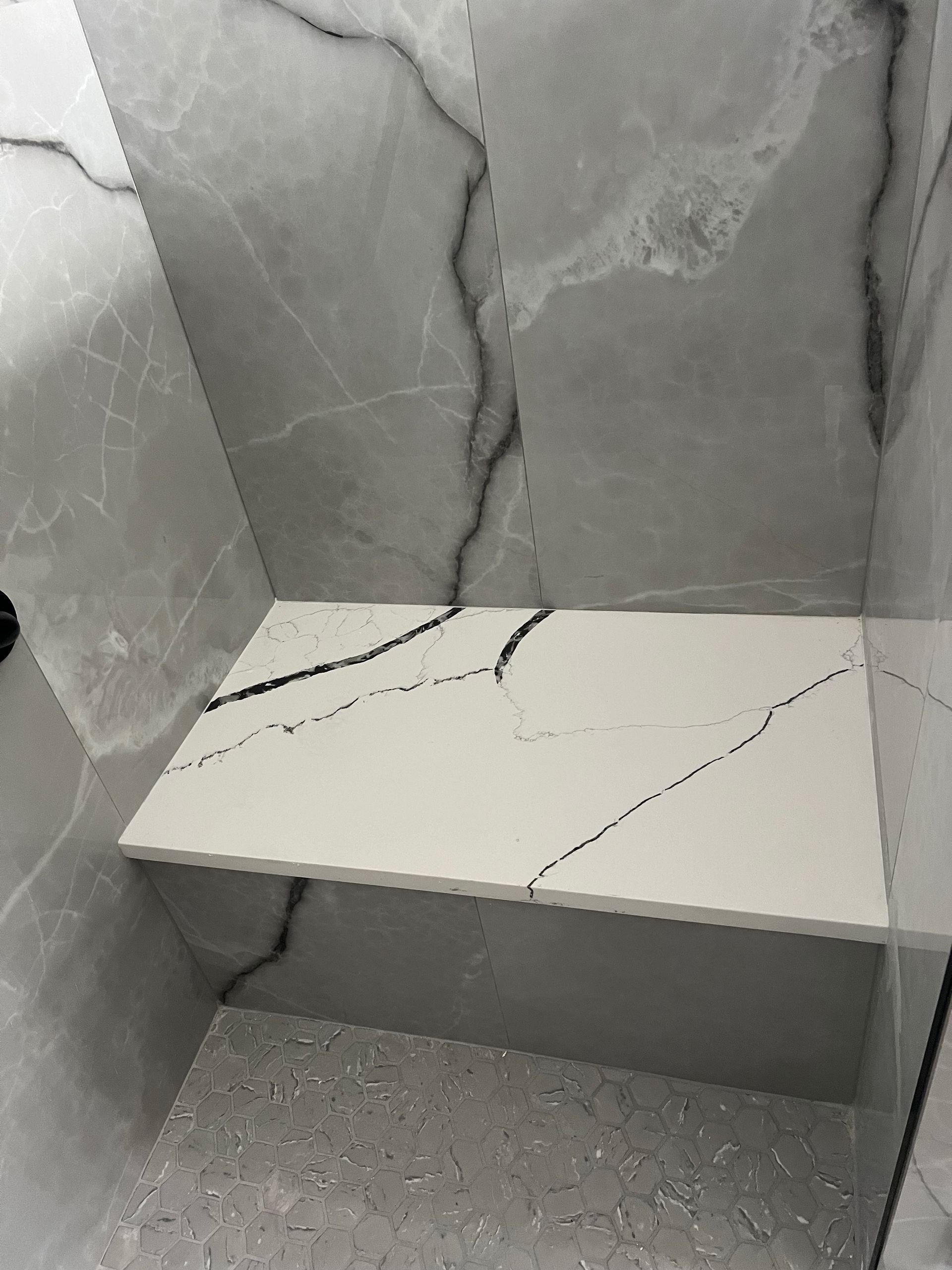 A white shelf in a bathroom next to a marble wall.