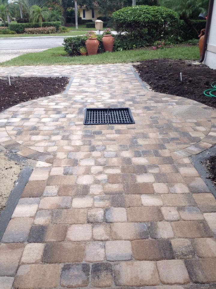 A brick walkway with a drain in the middle of it.