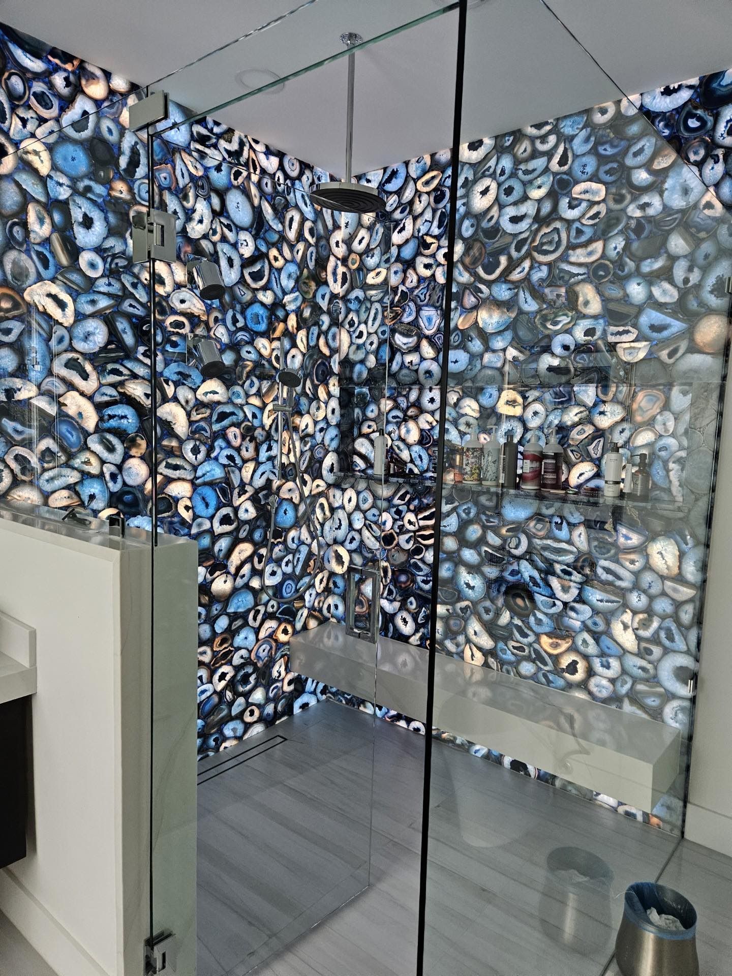 A bathroom with a printed wall and a glass shower door.