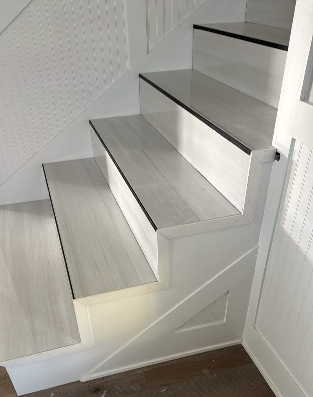 A white staircase with wooden steps and a white railing.