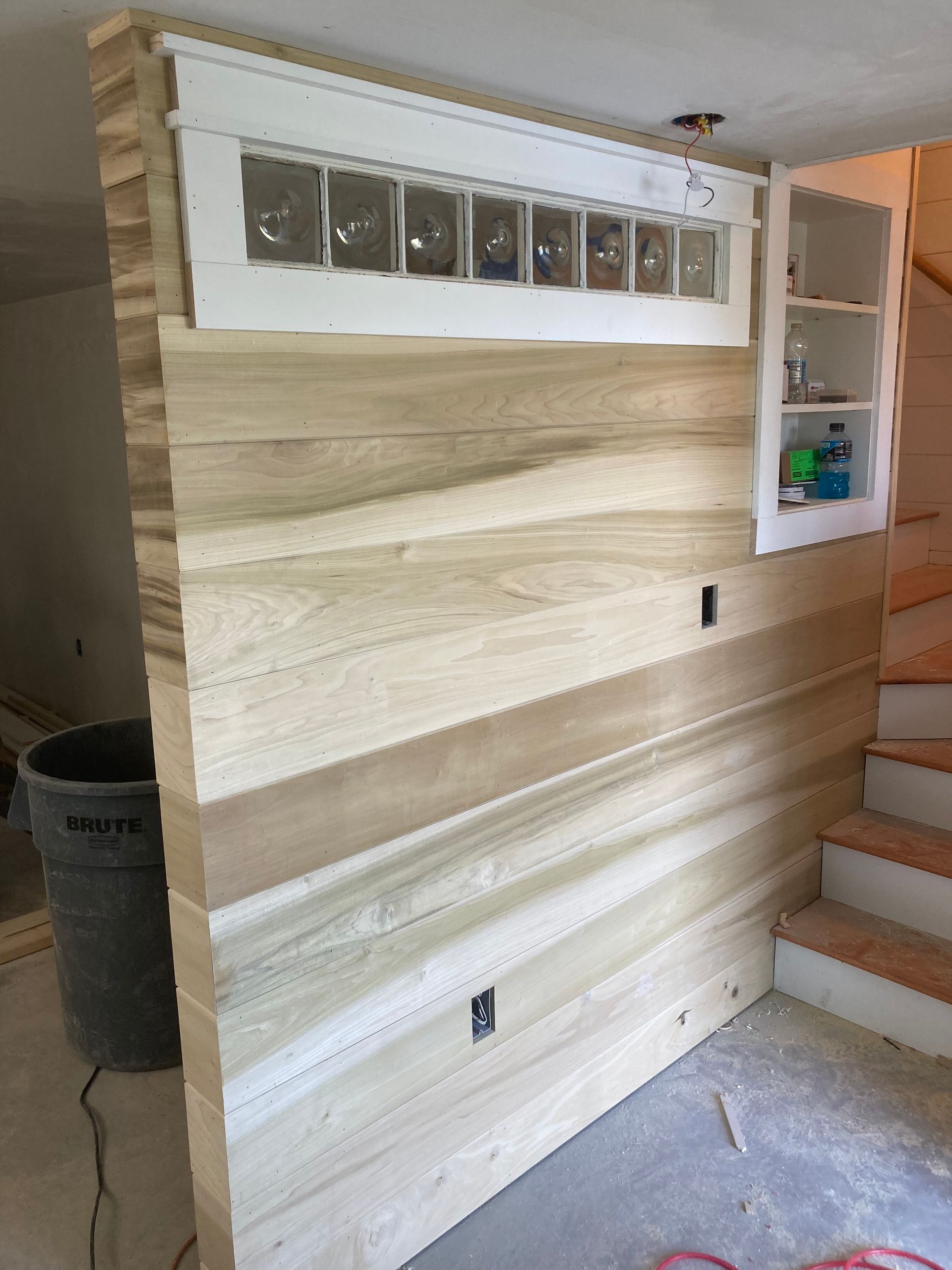 A wooden wall with a window and stairs in the background