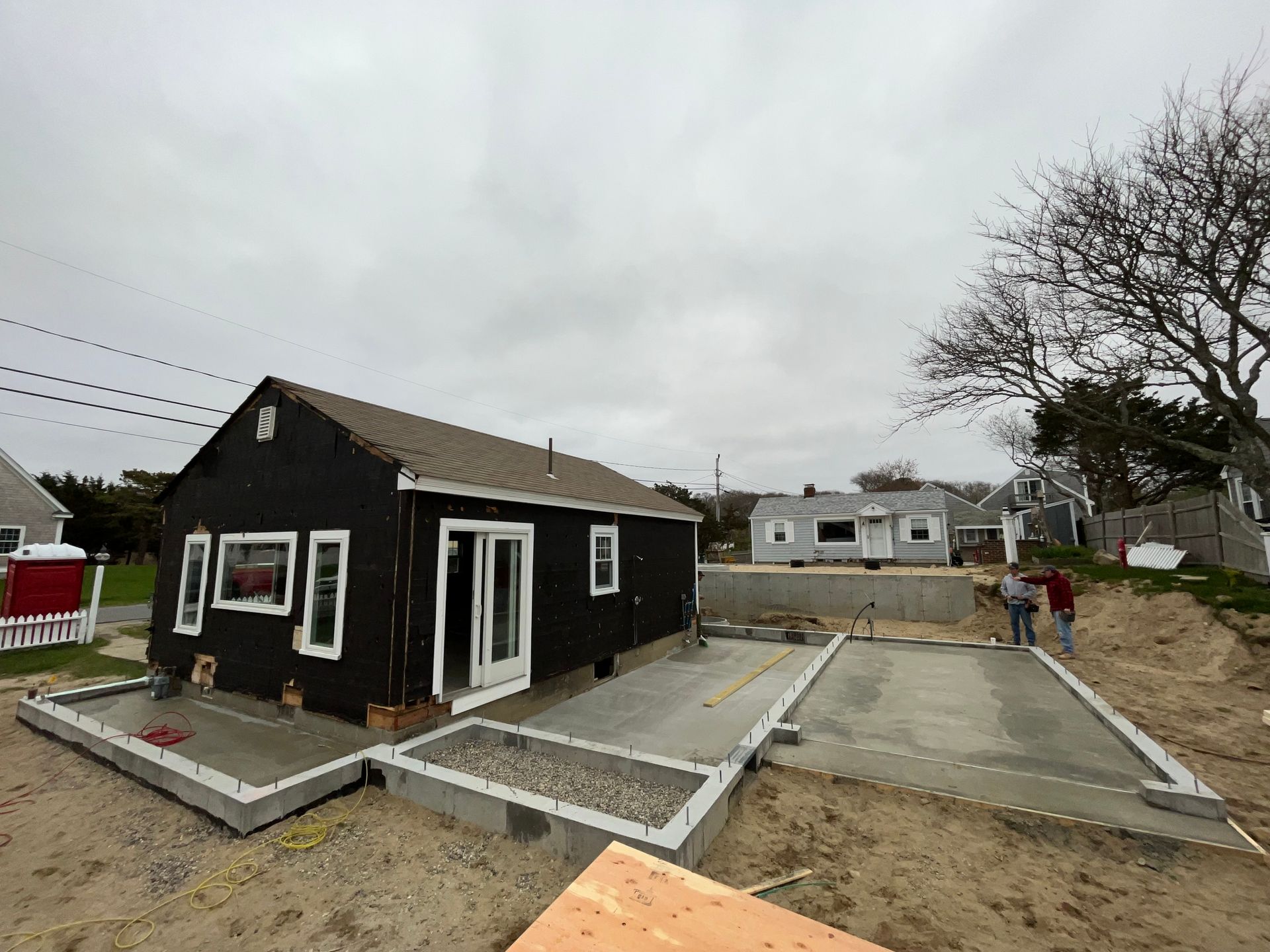 A black house is being built next to a concrete driveway