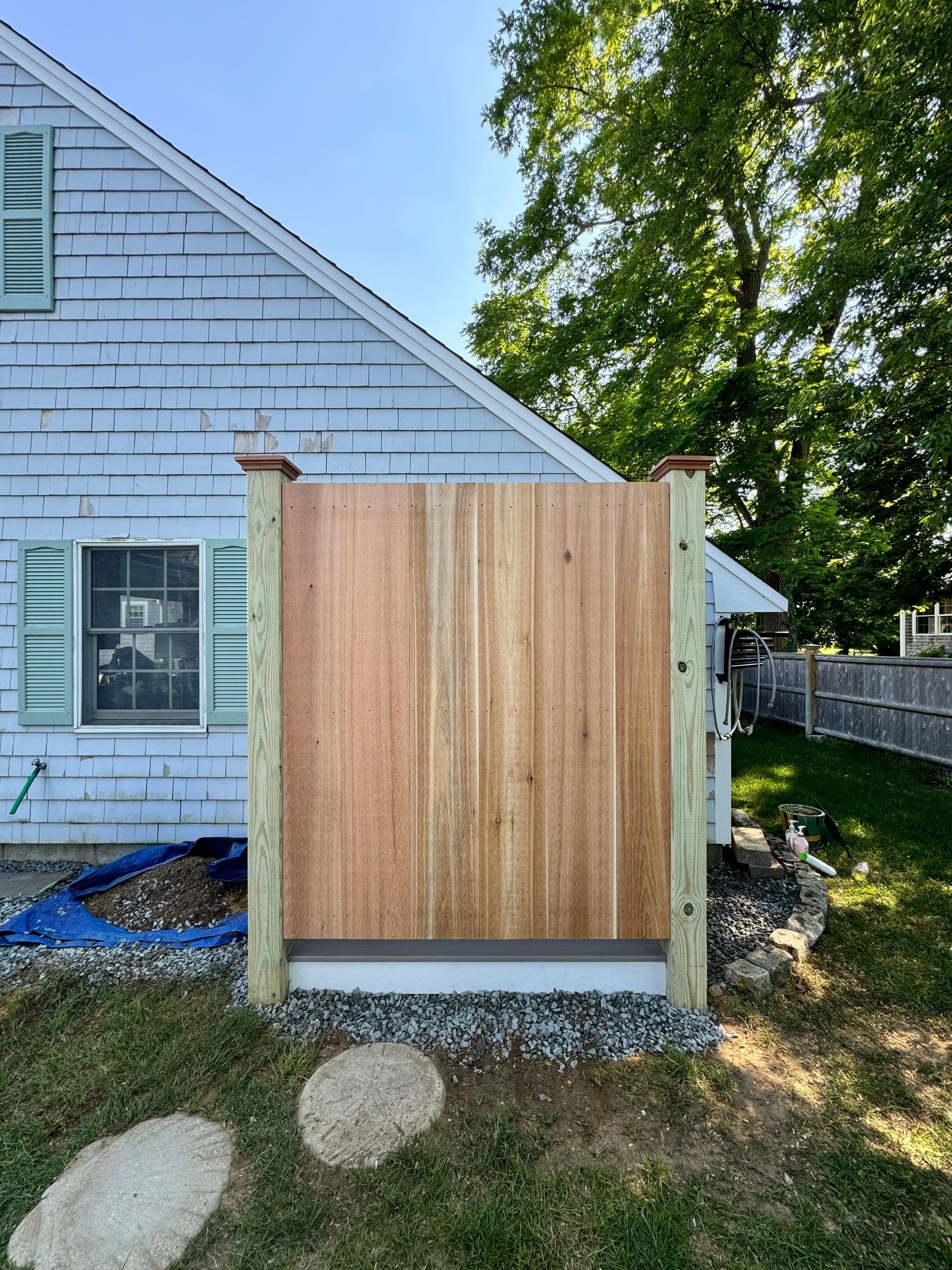 A wooden fence is sitting in front of a white brick house