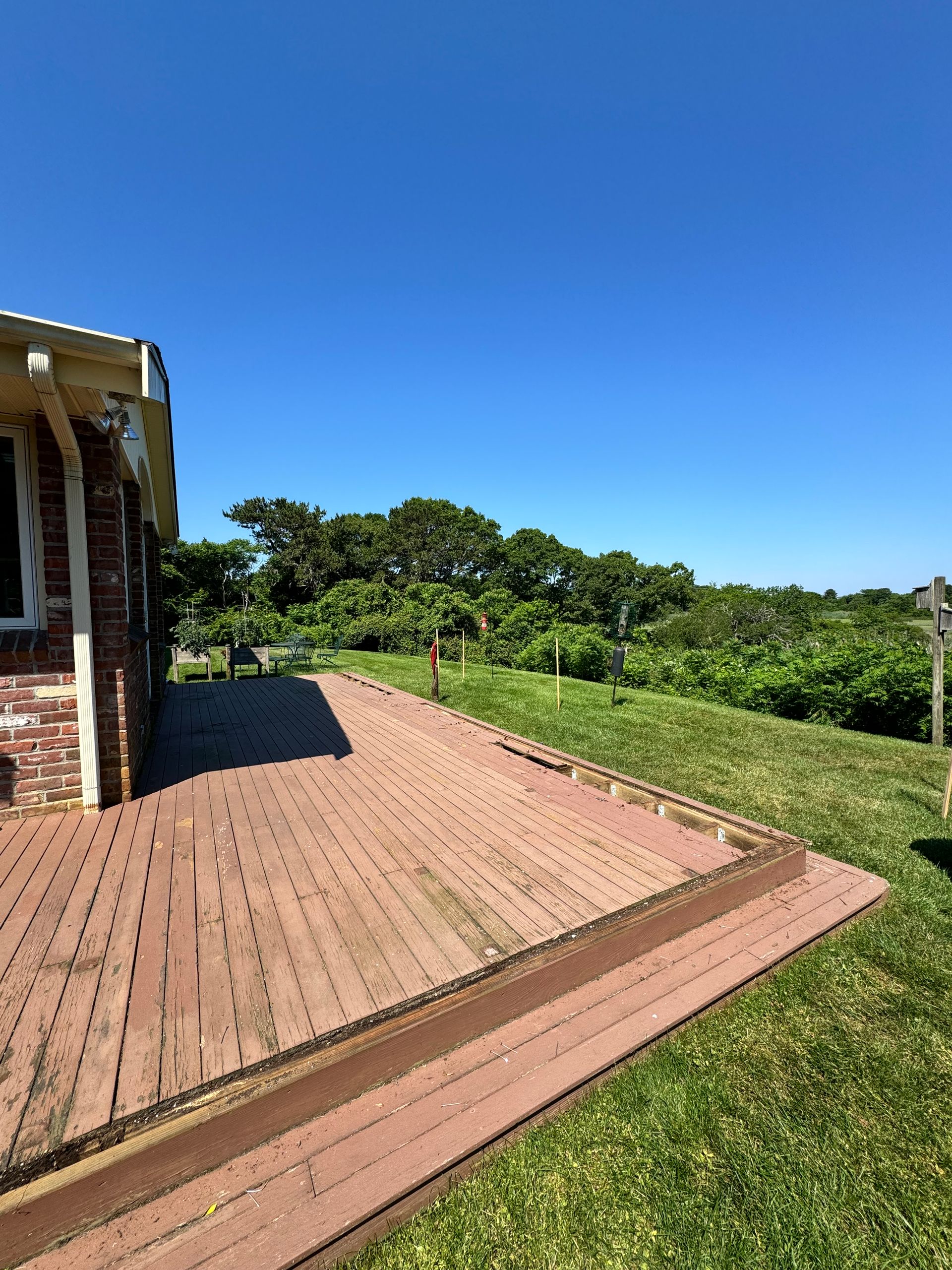 A brick walkway leading to a house with a lush green field in the background