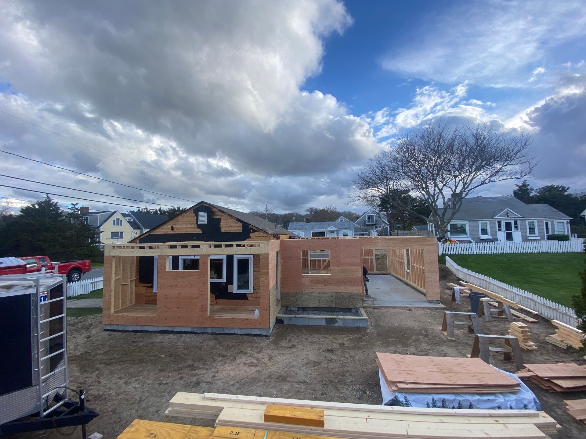 A house is being built in a yard with a lot of wood in front of it