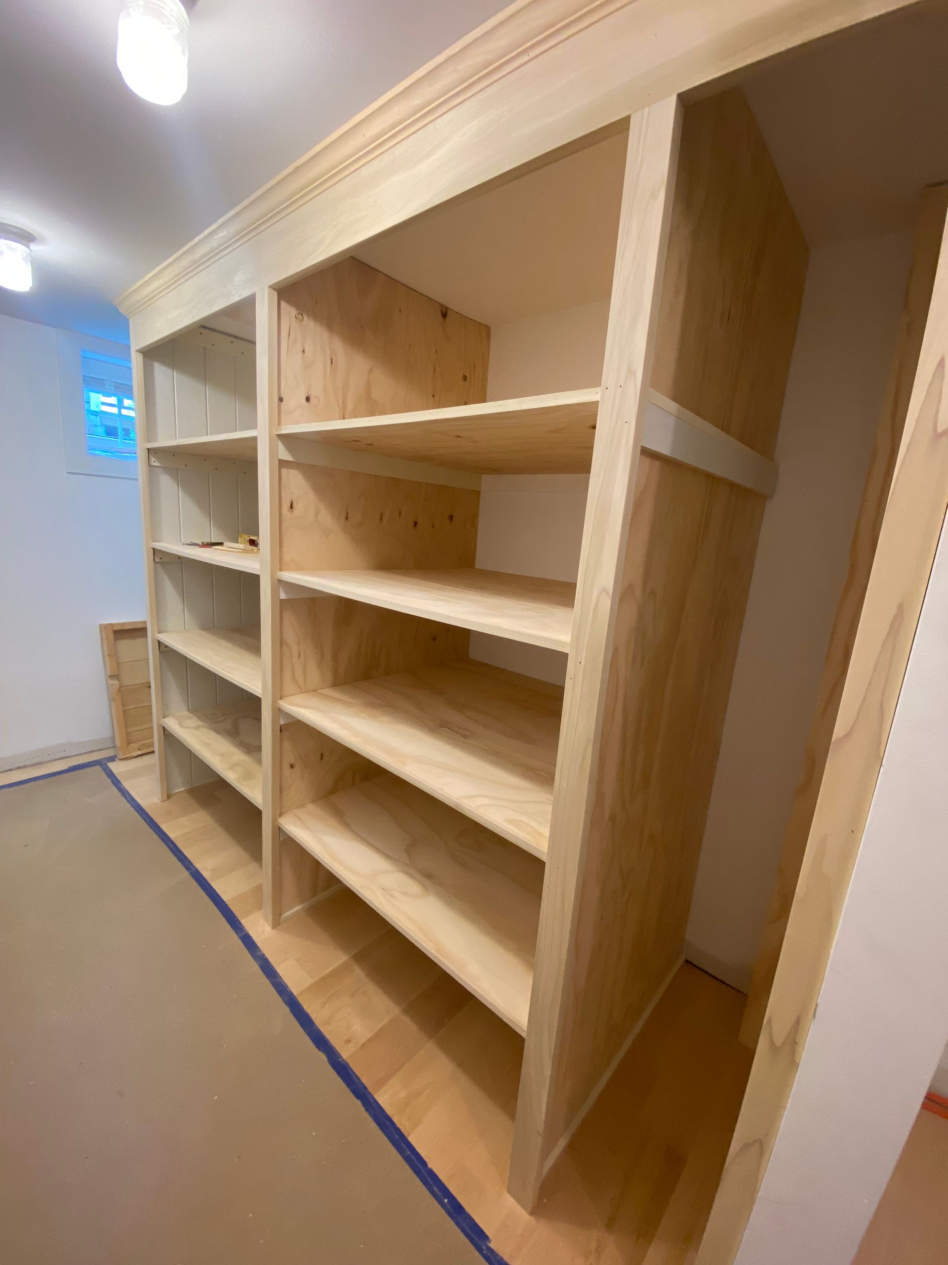 A closet with wooden shelves and a blue tape on the floor