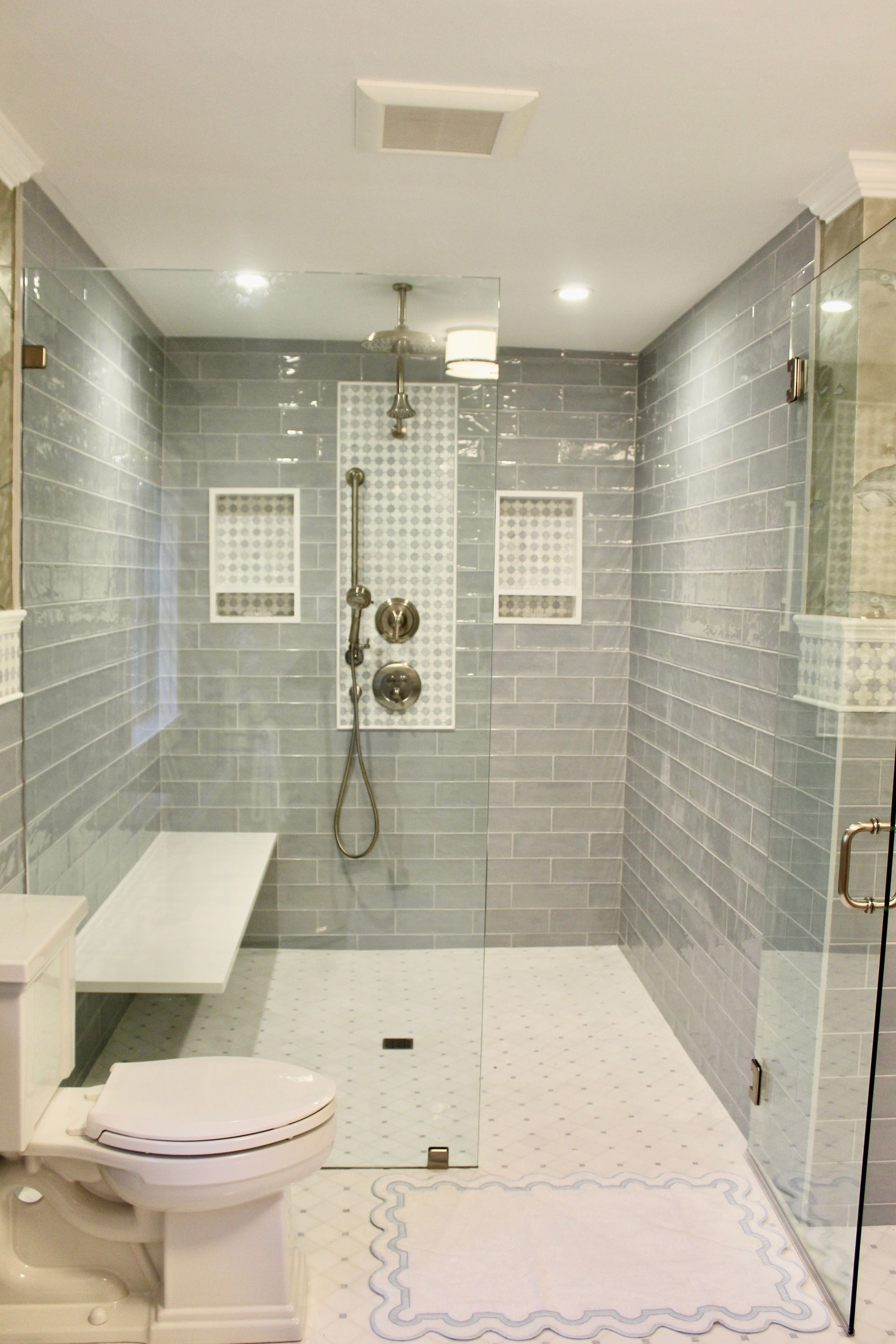 A bathroom with a toilet, shower, and bench