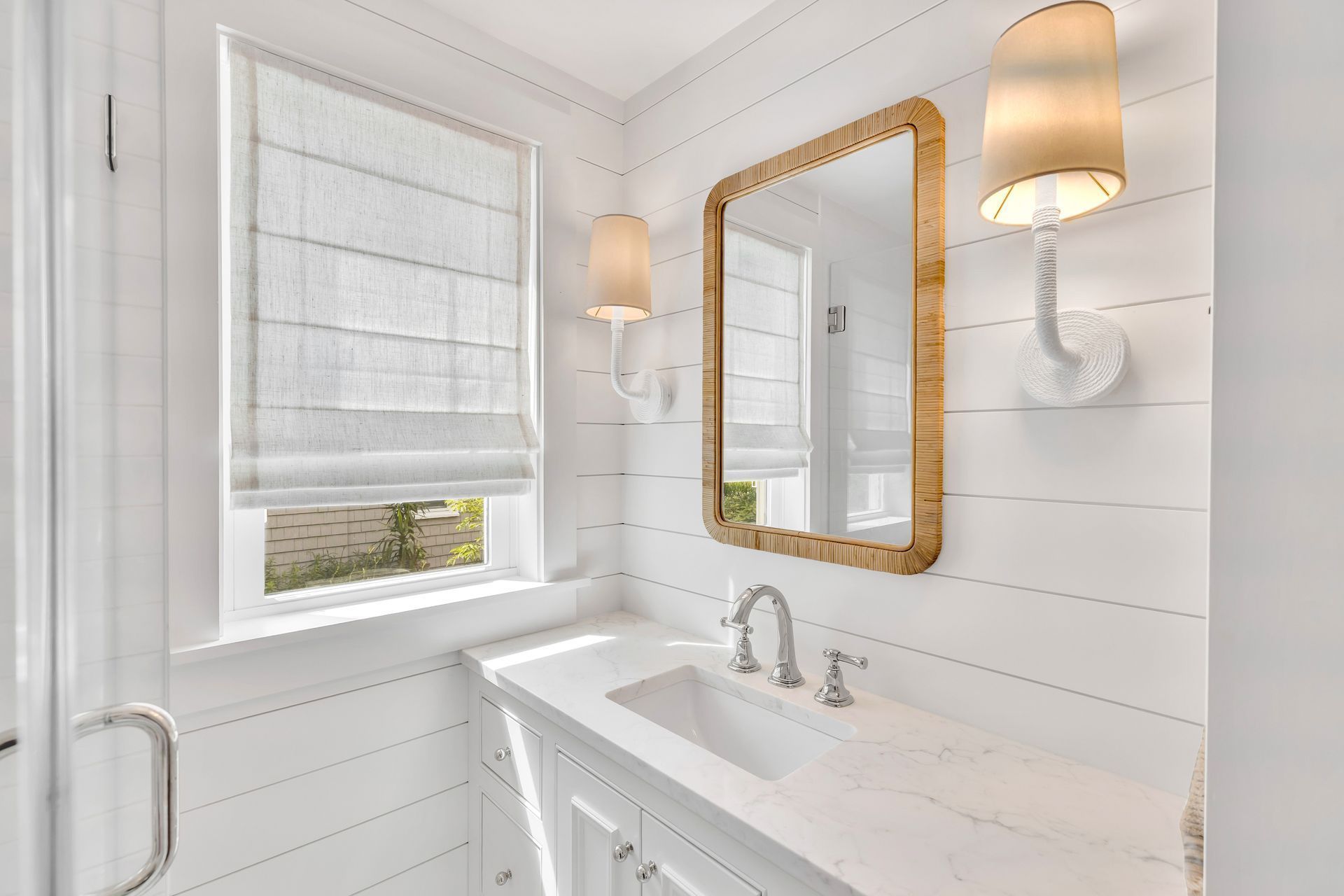 Bright white bathroom with vanity, mirror, window, and wall sconces