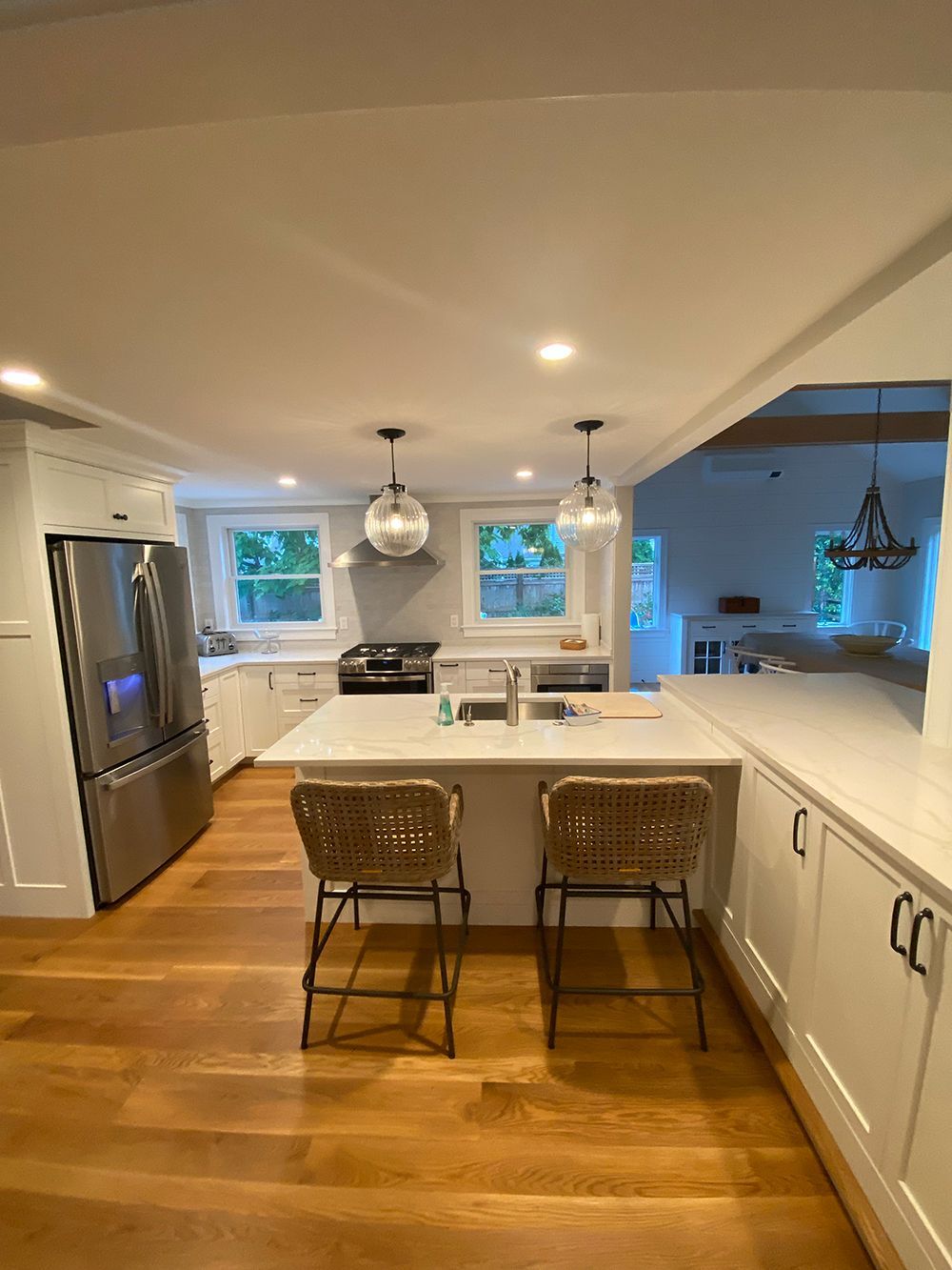 A kitchen with white cabinets, stainless steel appliances, hardwood floors and a large island.