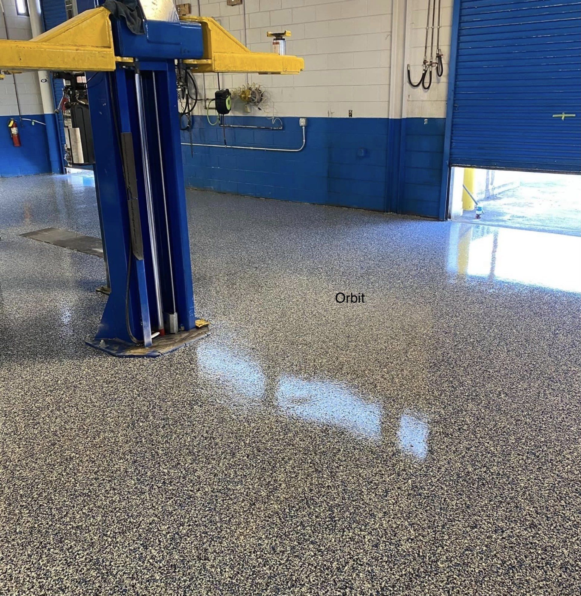 a blue and yellow lift is in a garage with a concrete floor .