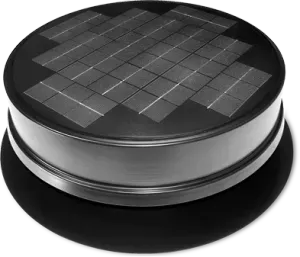 Close-up of a circular black device with a grid of square insets on top, sitting on a base.