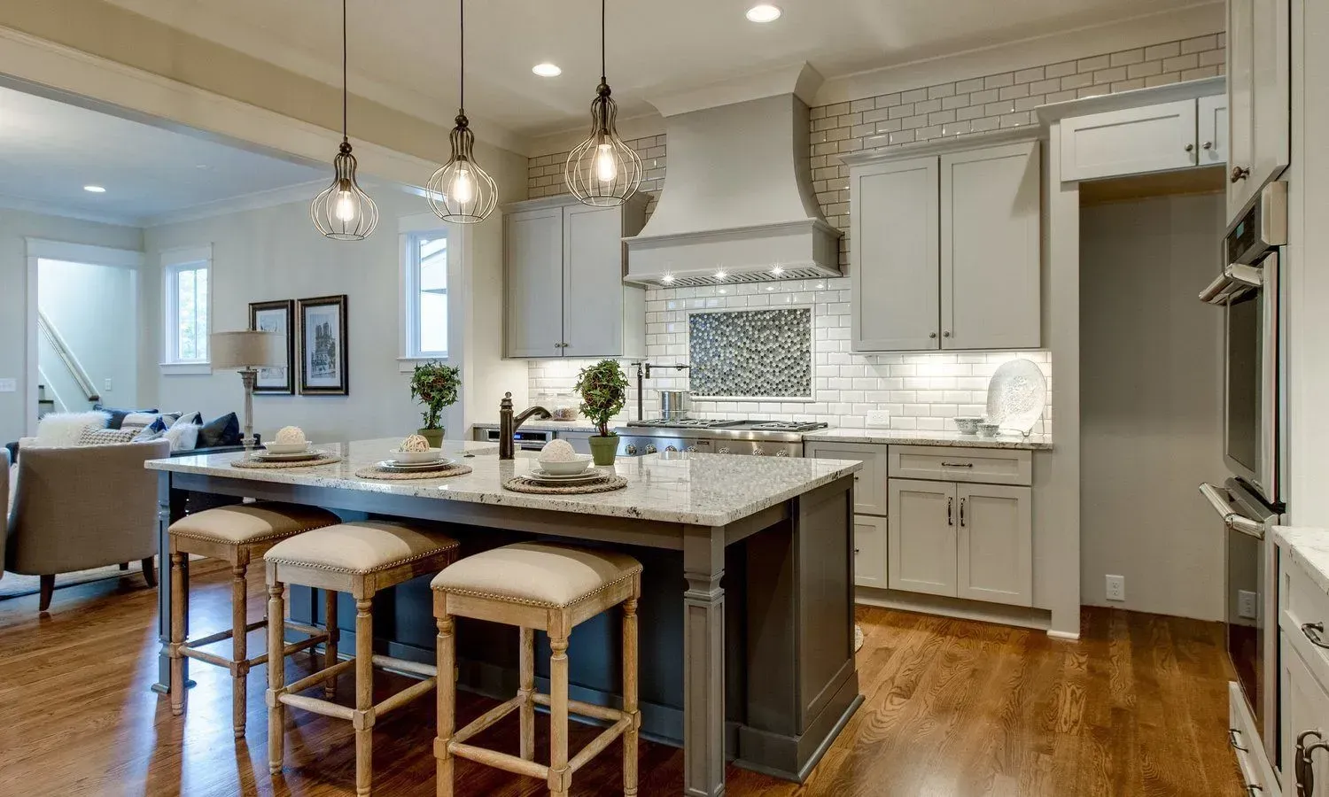 Elegant kitchen with an island, cabinets, and three hanging lights.