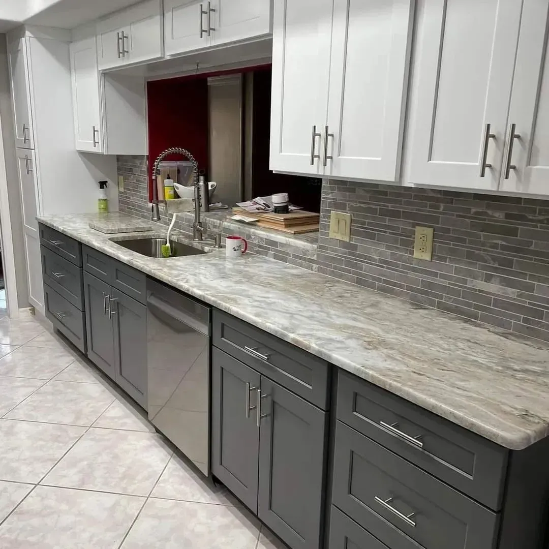 Kitchen with white upper cabinets and gray lower cabinets, stainless steel appliances, and a tiled backsplash.