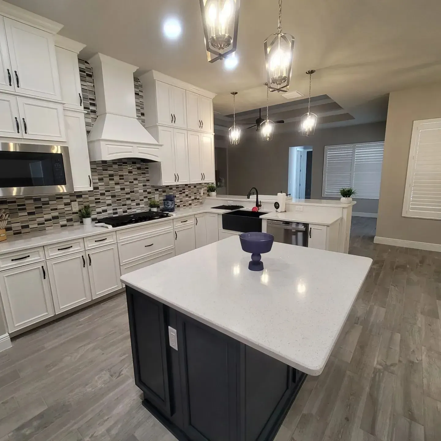 Modern kitchen with white cabinets, dark island, and light countertops.