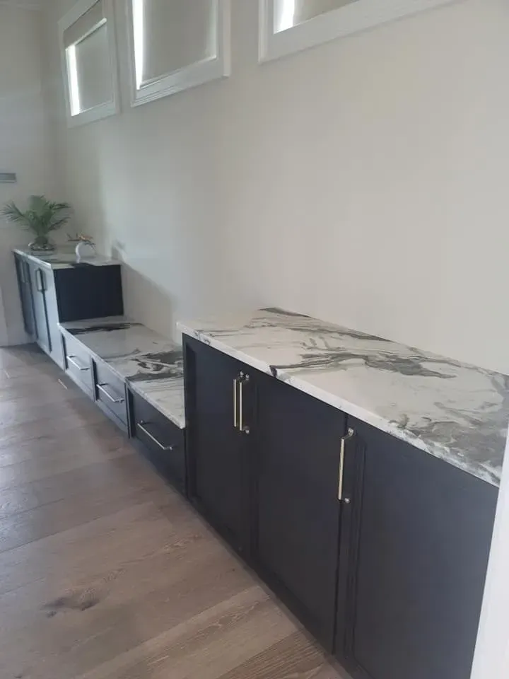 Dark cabinets with marble countertops along a wall. Light wooden floor.