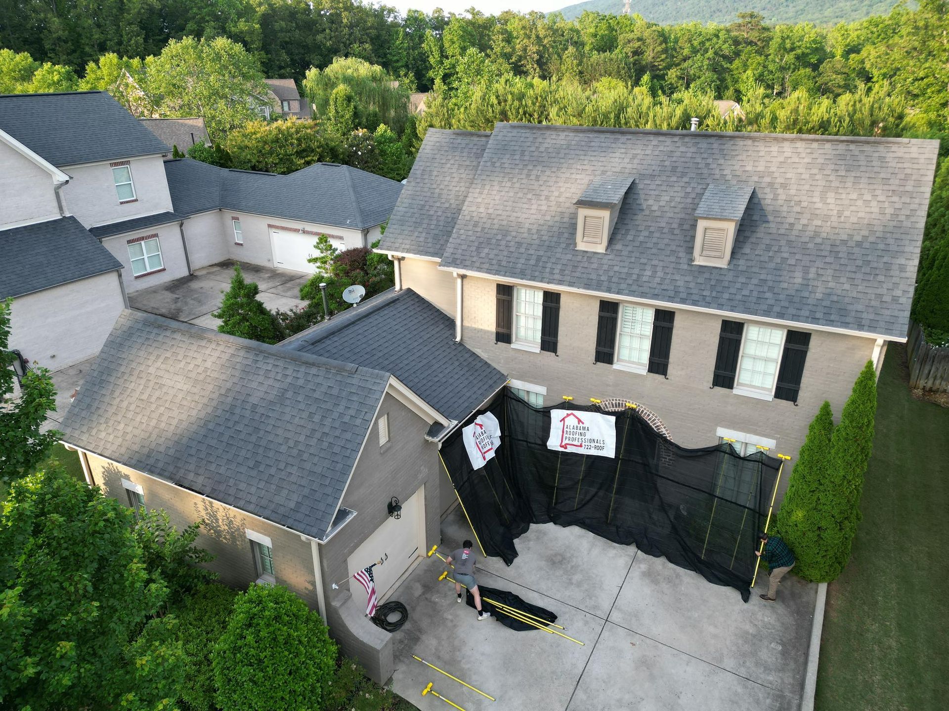 House with black netting around a garage; potential construction work in progress.