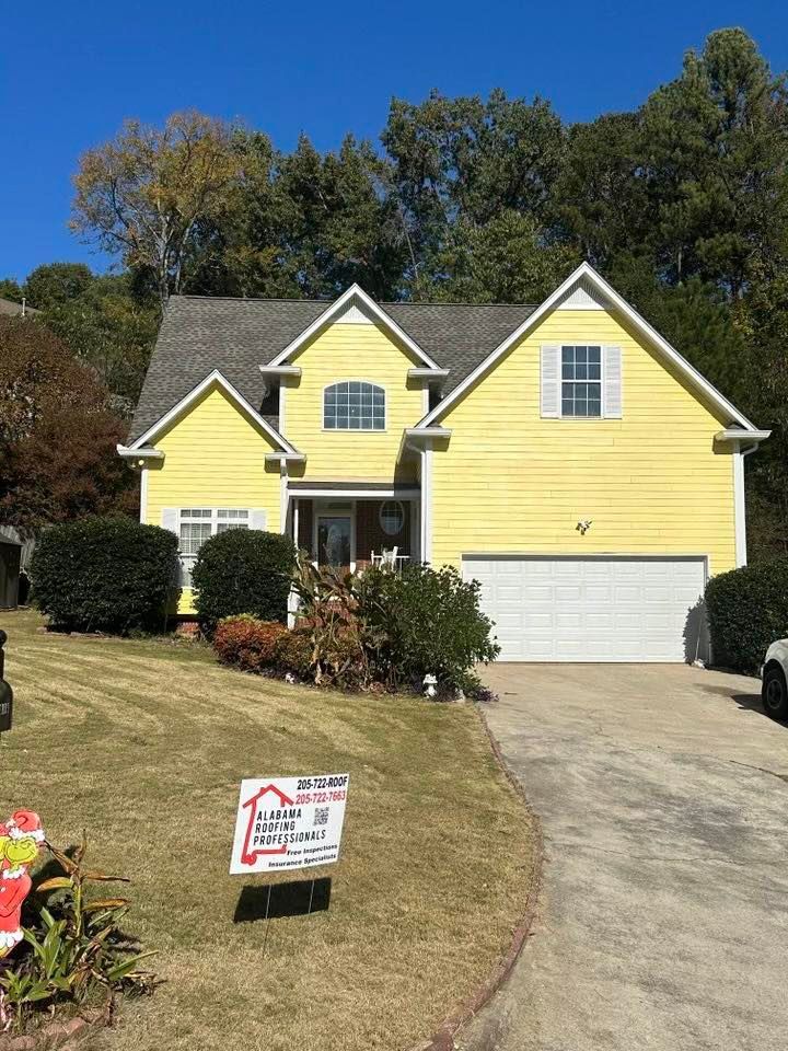 Yellow house with white garage door and shutters; sign in front.