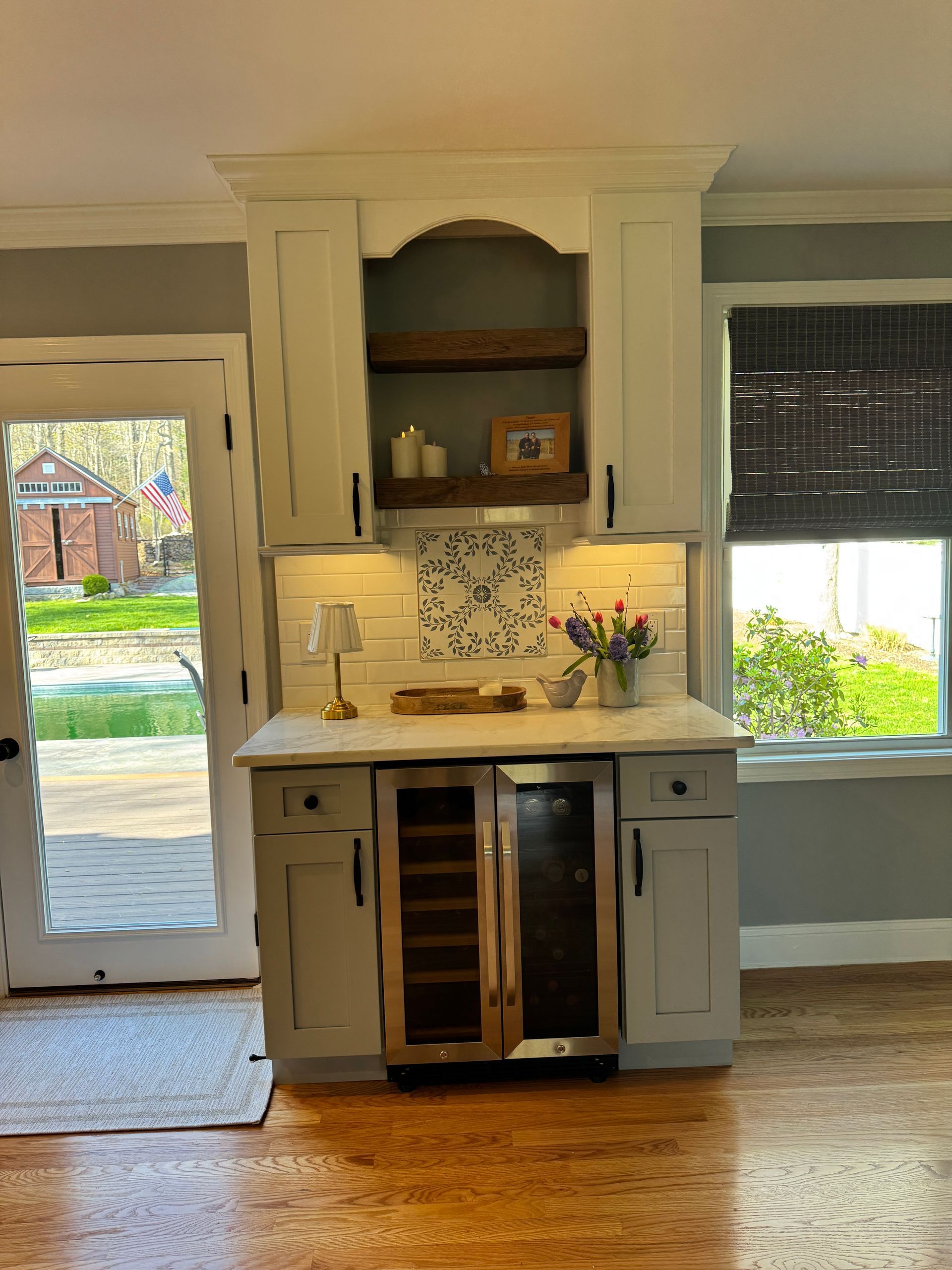 Small kitchen with cream cabinets, tiled backsplash, sink, and glass door and window overlooking a yard.