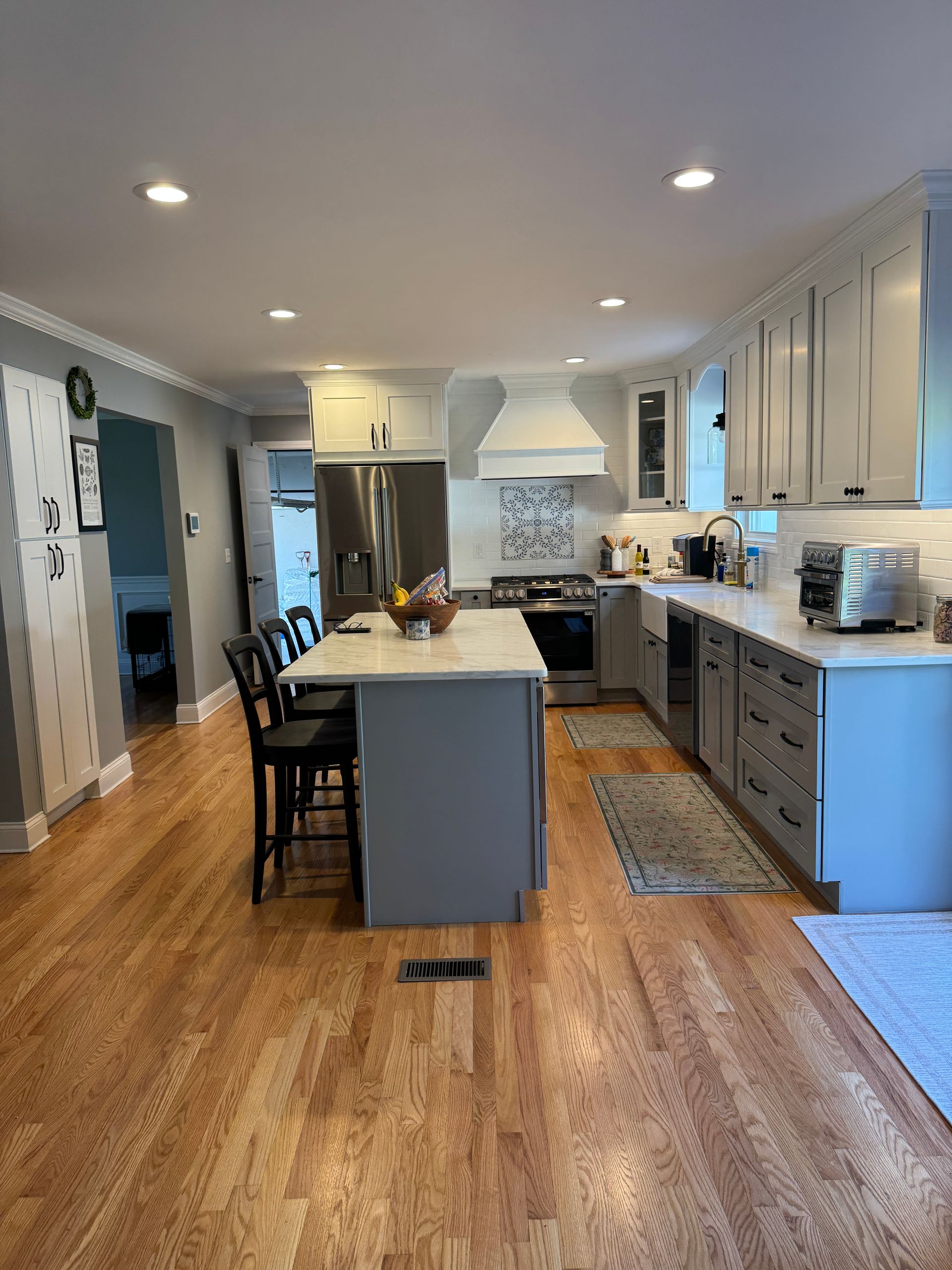 Bright modern kitchen with white cabinets, island seating, and hardwood floors