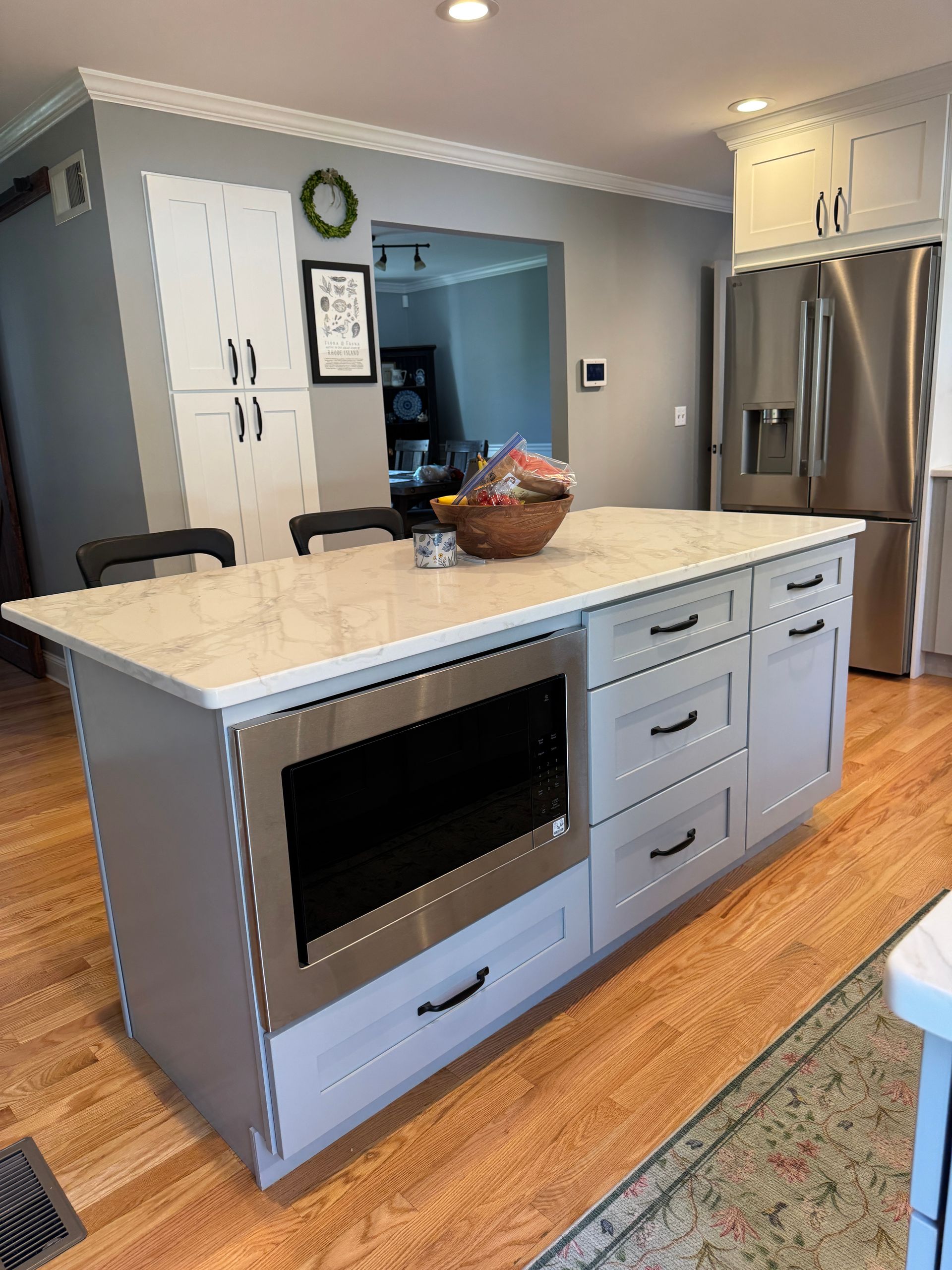 Kitchen island with a light stone countertop, drawers, and a built-in oven in a modern kitchen