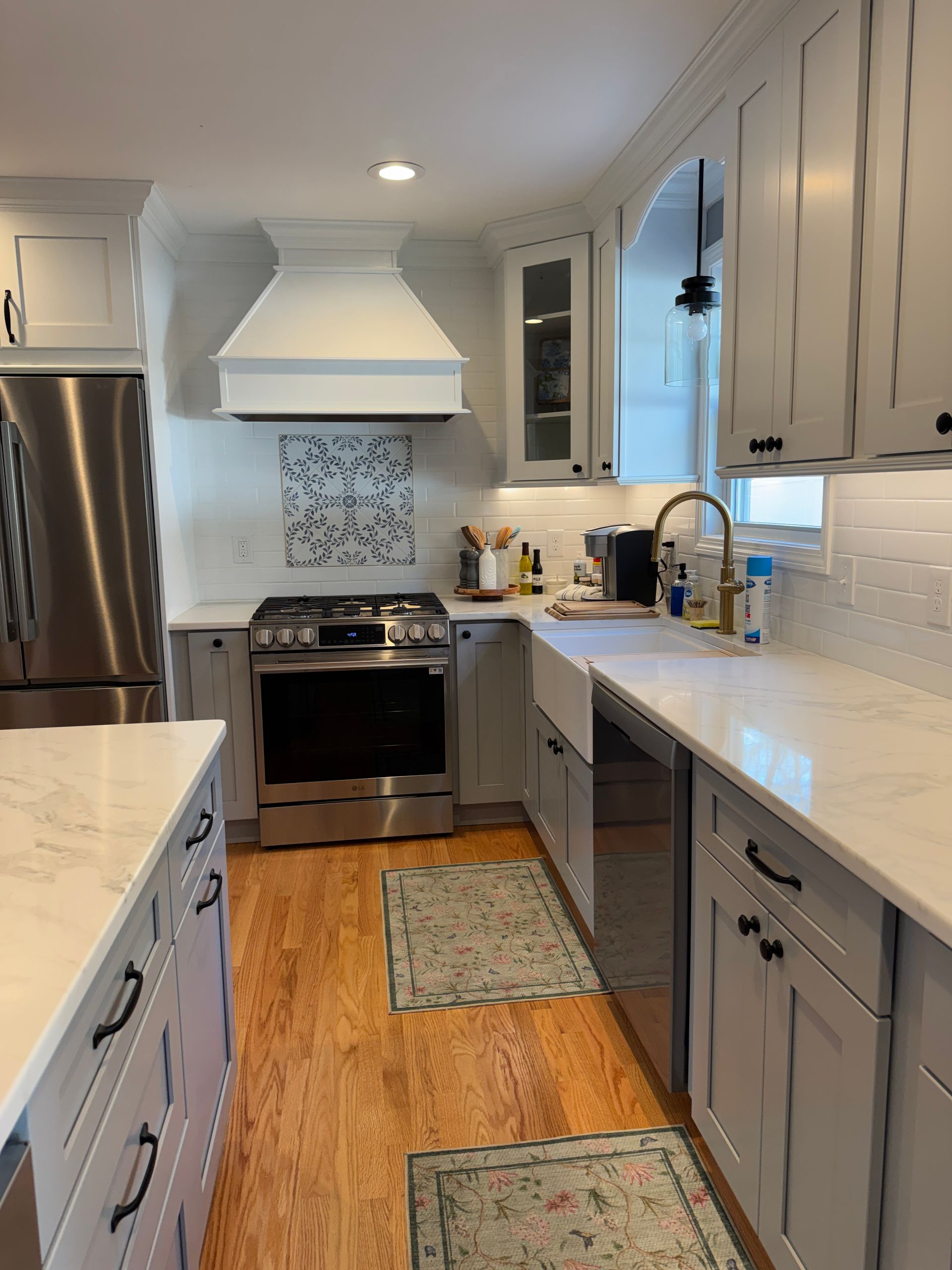 Bright modern kitchen with white cabinets, stainless appliances, and a hardwood floor runner.