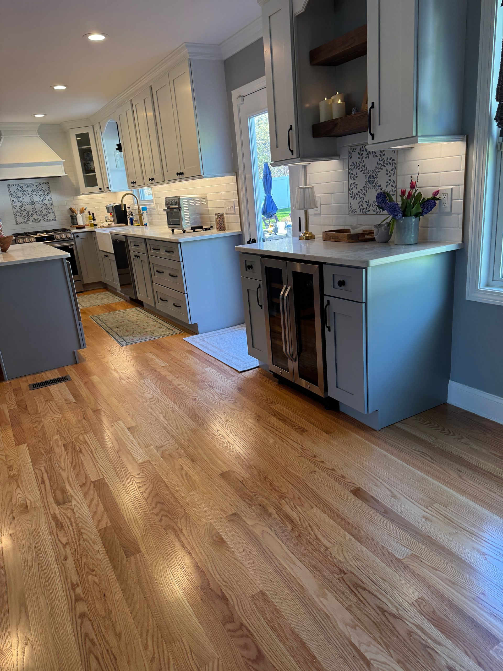 Bright modern kitchen with light wood floors, white cabinets, and a blue island or counter area