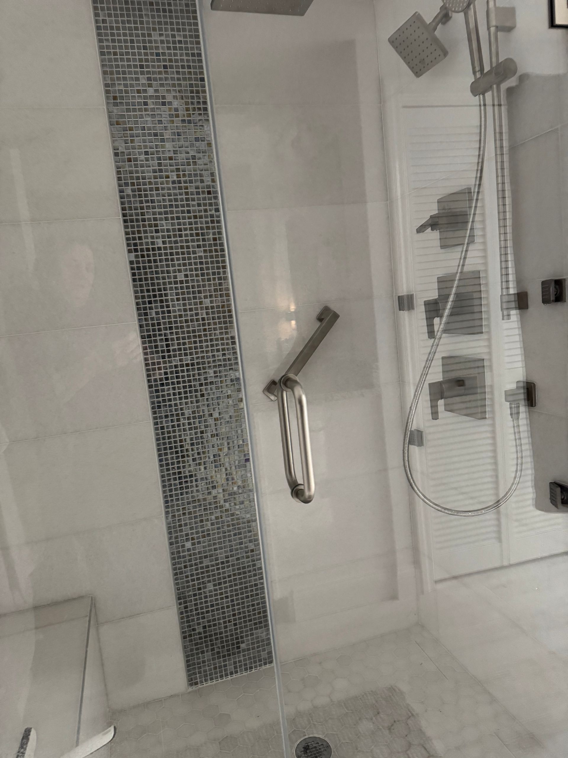 Modern bathroom shower with glass enclosure, tiled walls, and chrome fixtures