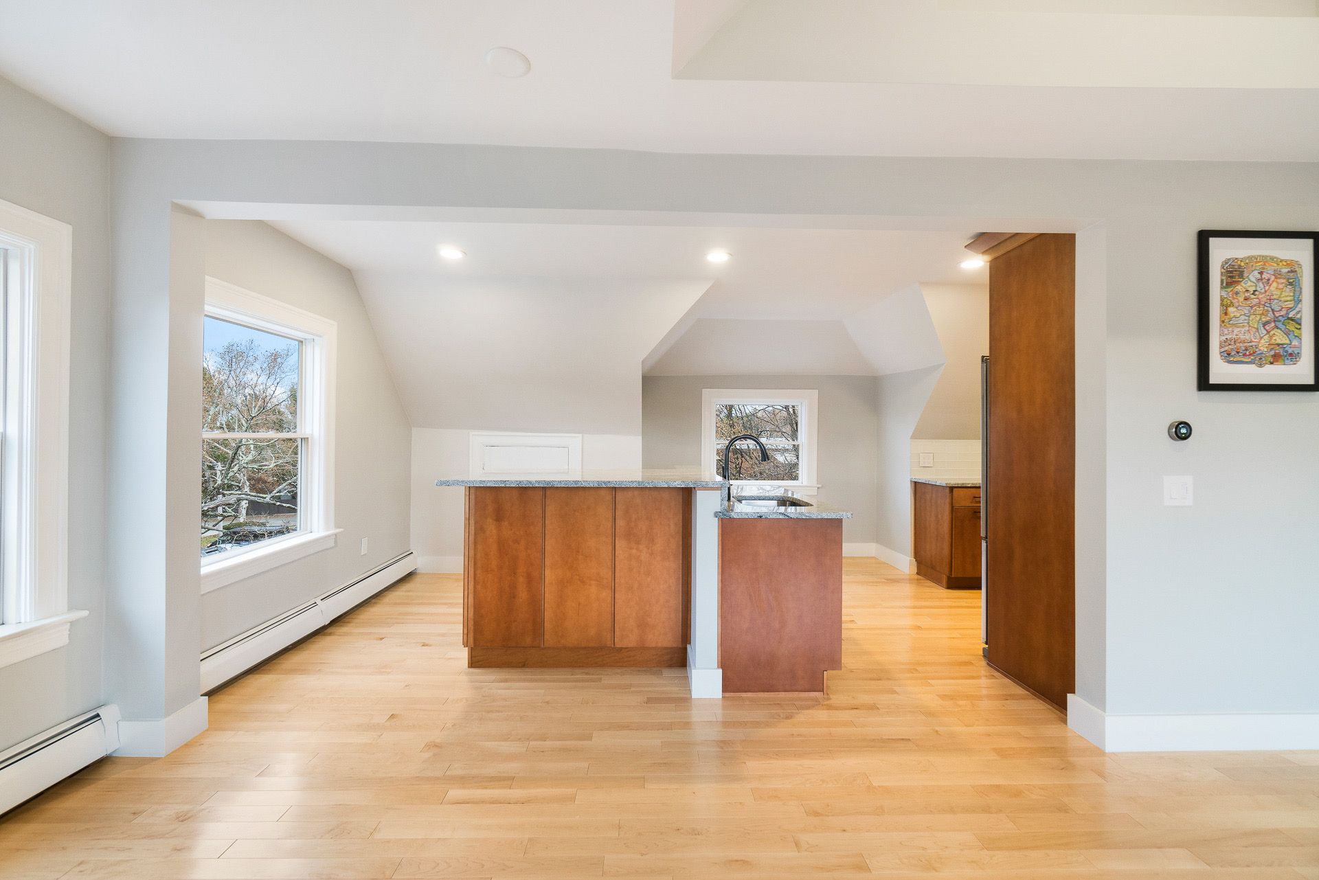Bright open kitchen with wooden island, light hardwood floors, and large windows in a white interior