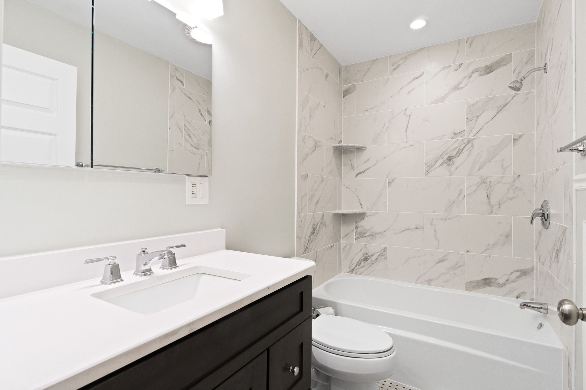 Modern white bathroom with vanity, mirror, and marble shower/tub surround