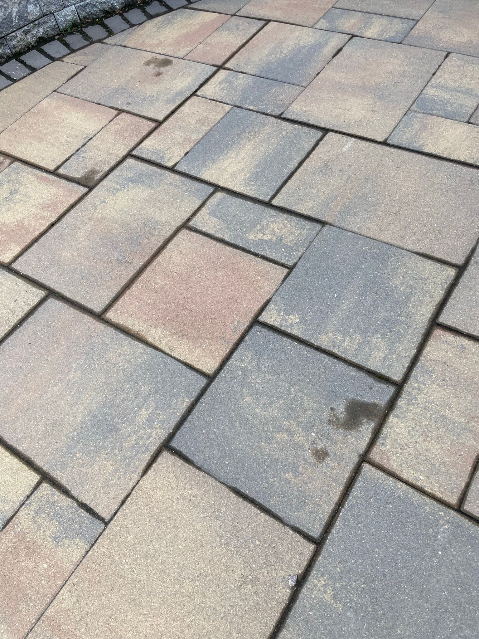 Close-up of gray and tan interlocking paver stones with a few dark stains