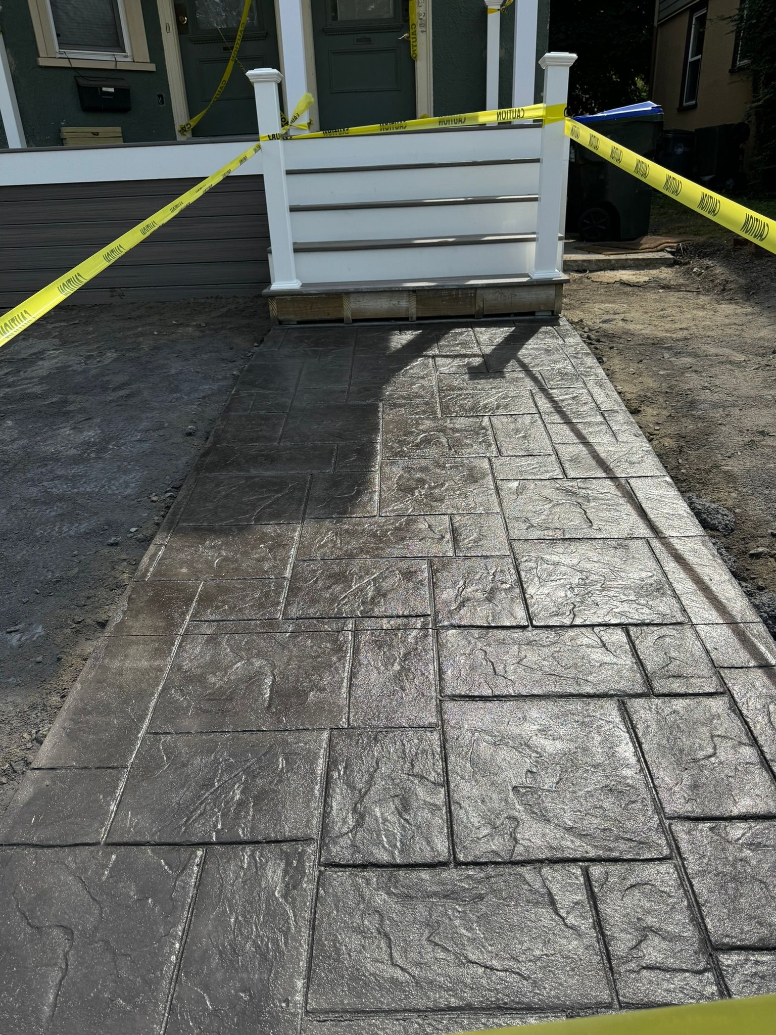 Blocked walkway with caution tape and a large white planter in front of a building entrance
