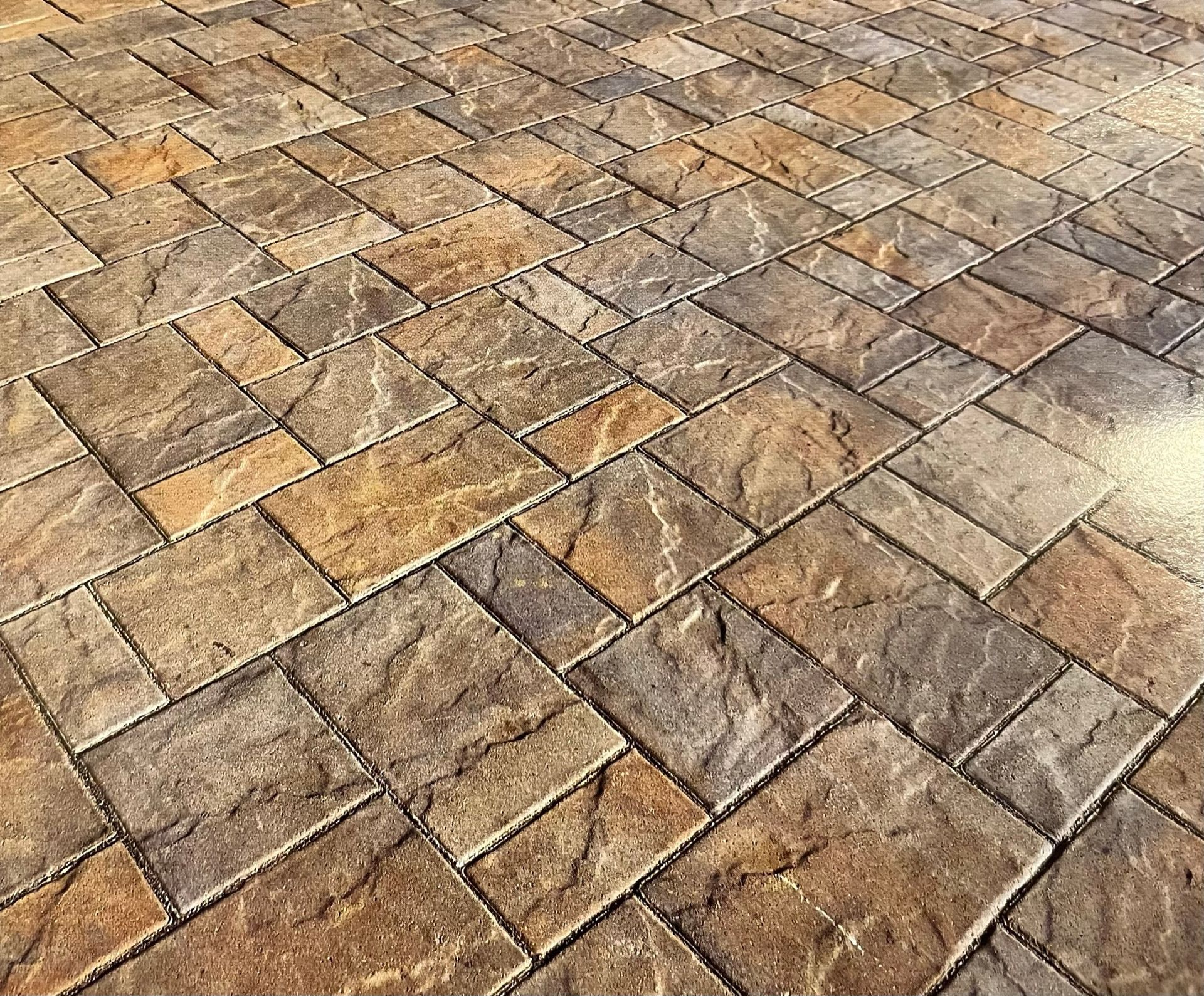 Stone patio with irregular tan and brown pavers in a diagonal pattern