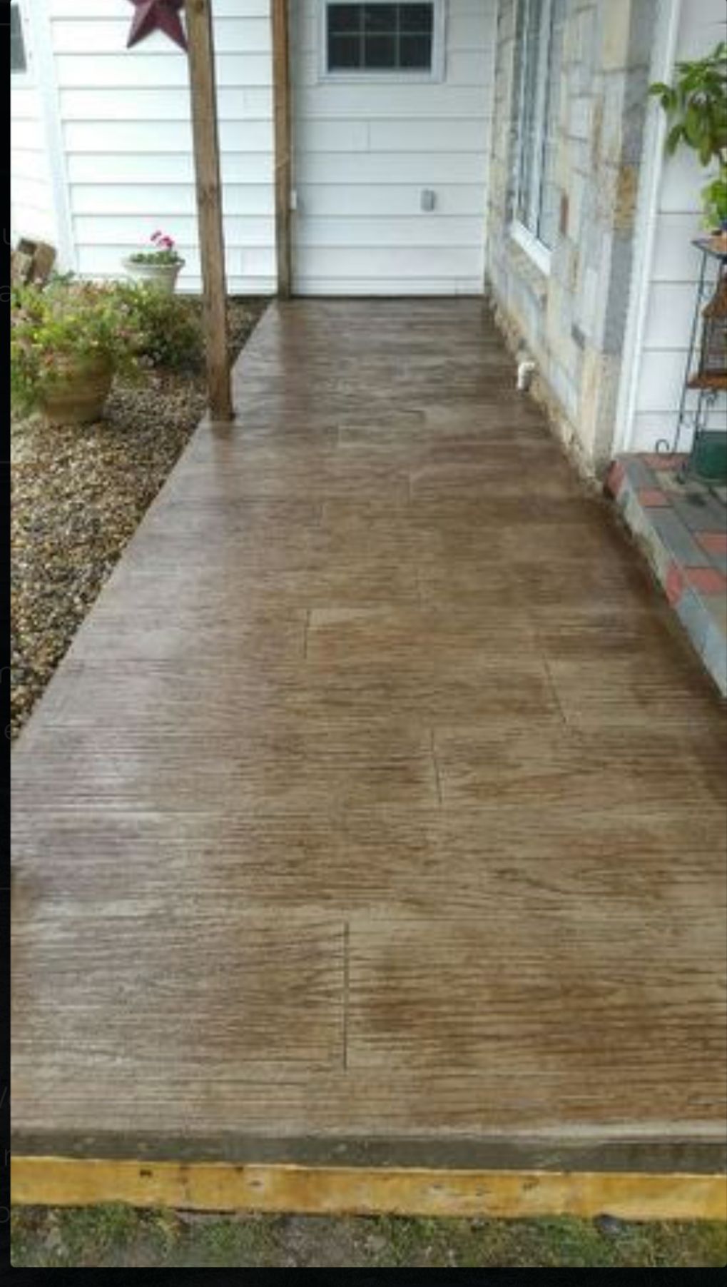 Wooden front porch walkway leading to a white door beside a house exterior