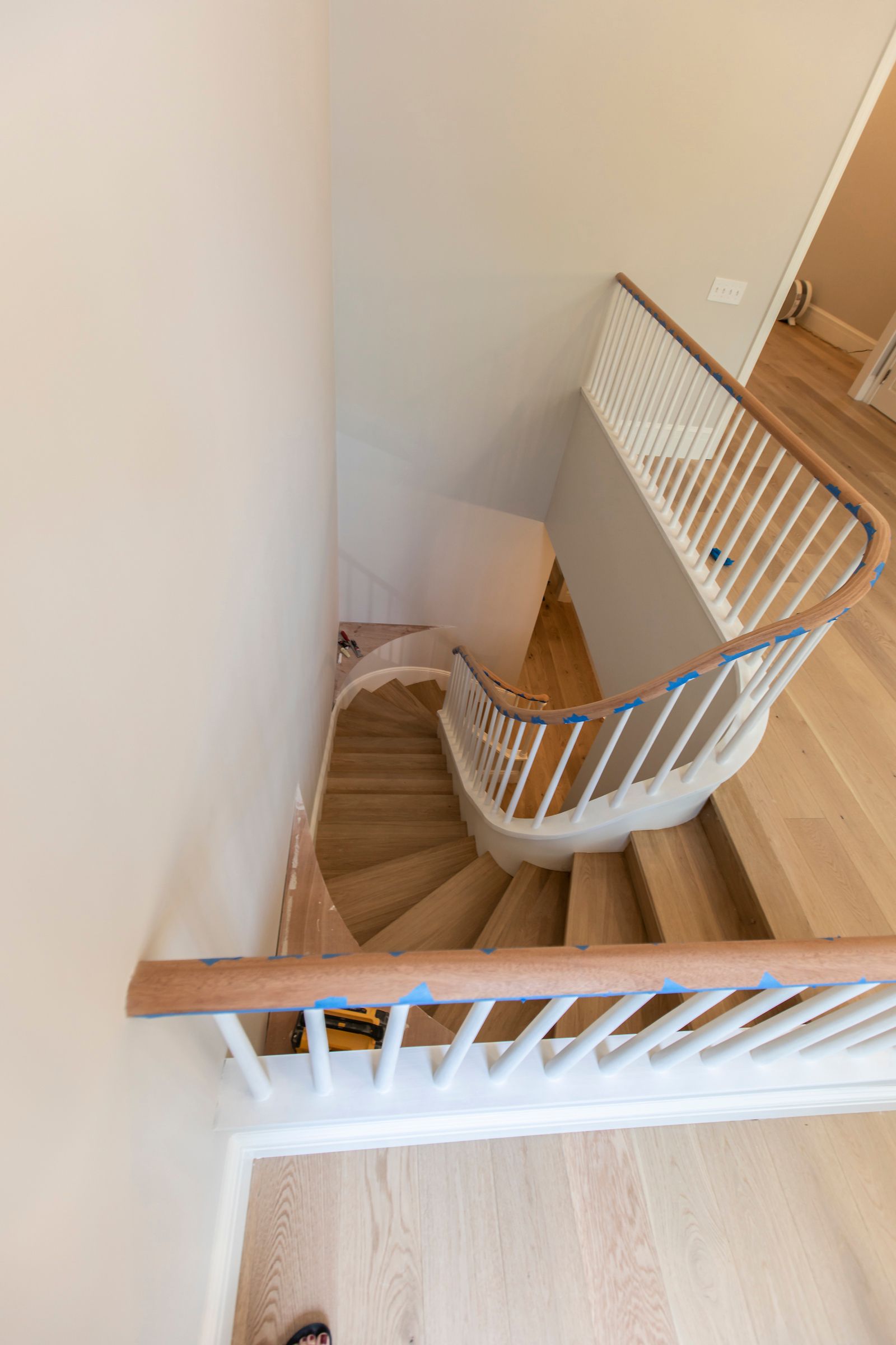 Curved wooden staircase with white railing viewed from above in a bright interior staircase landing