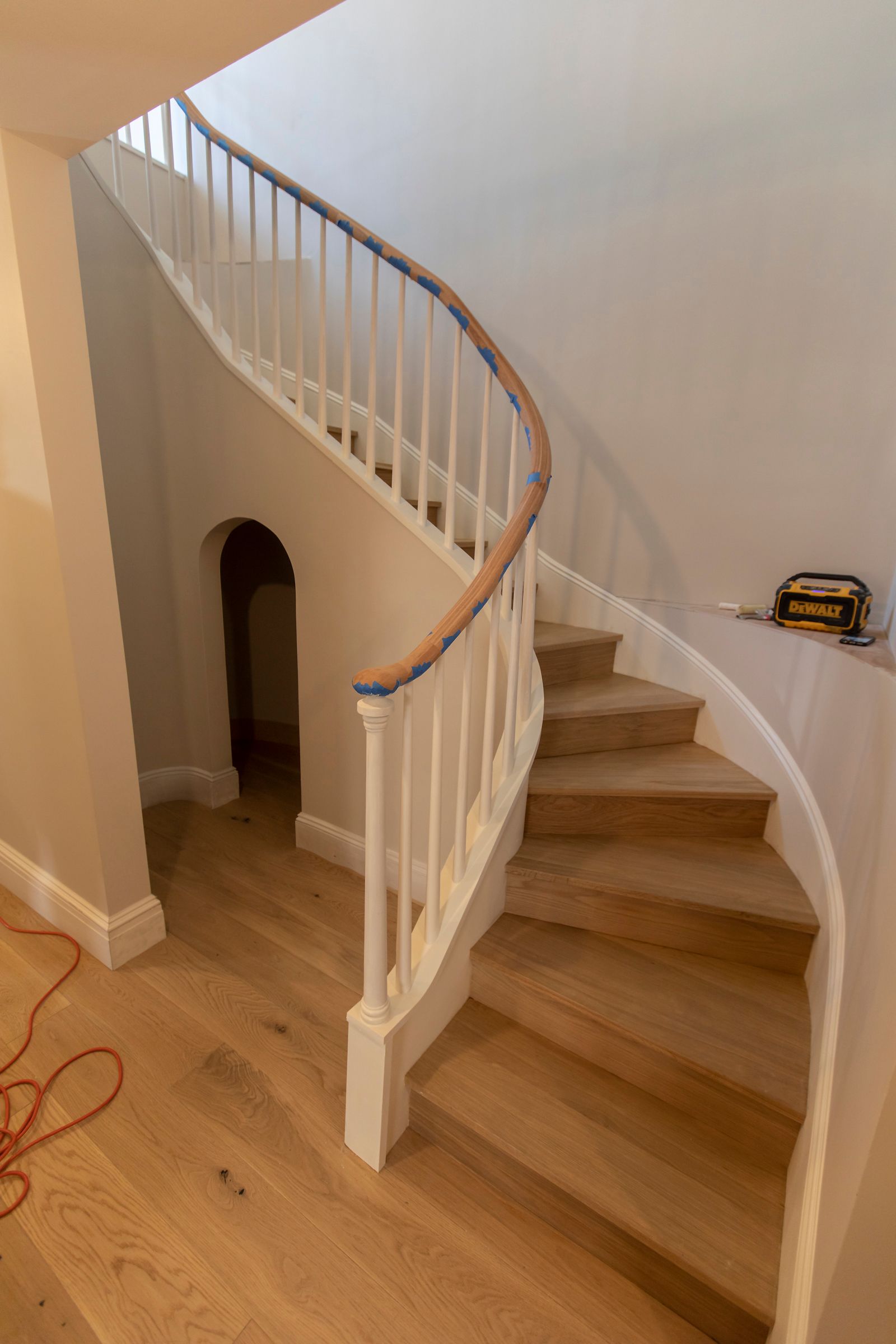 Curved wooden staircase with white railings in a home hallway.