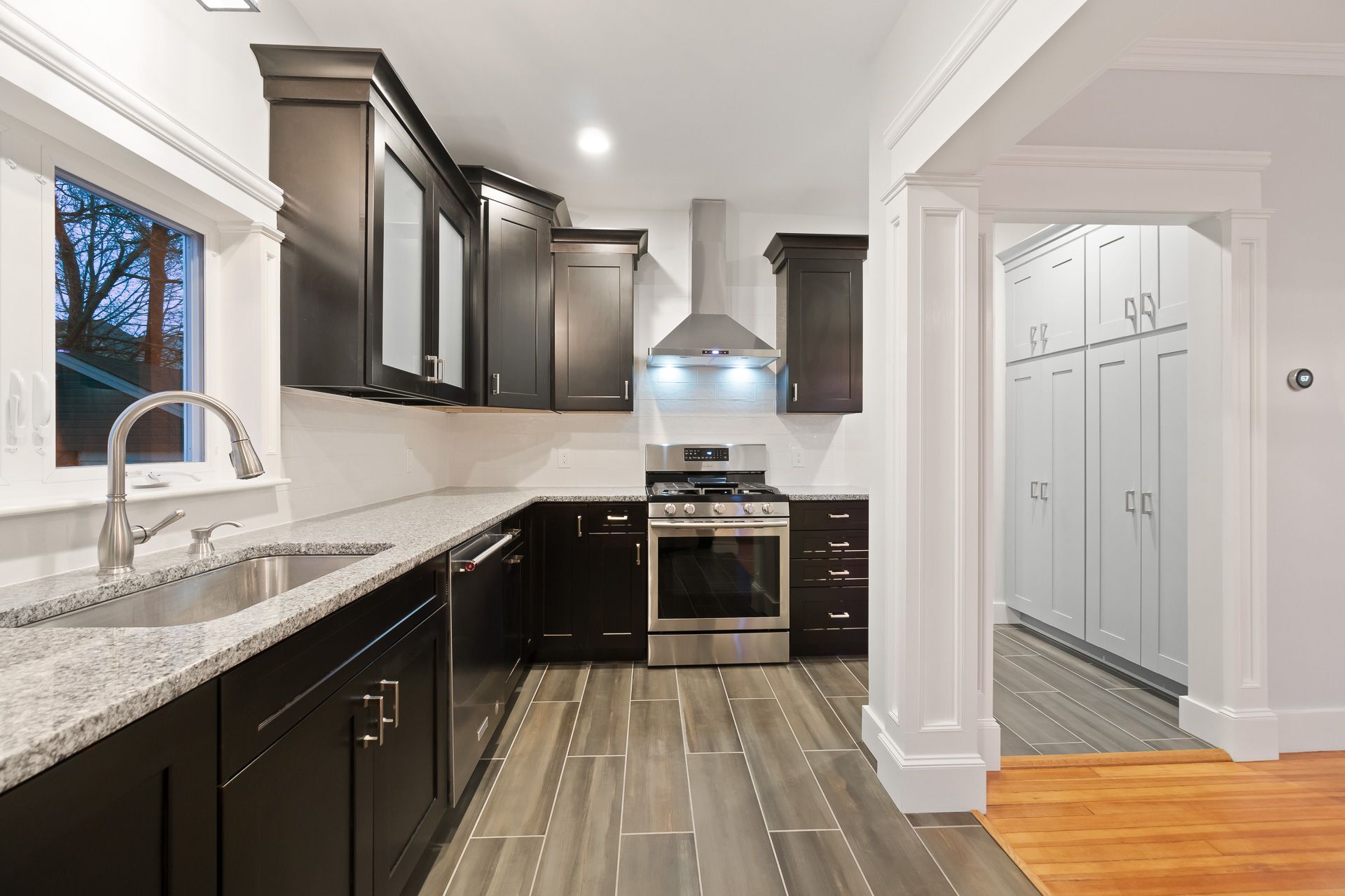 Modern kitchen with dark cabinets, stainless steel appliances, and gray countertops.