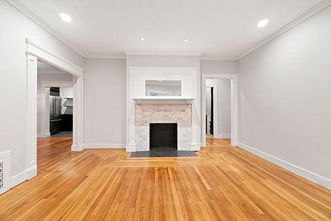Empty living room with wood floors, fireplace, and doorways.