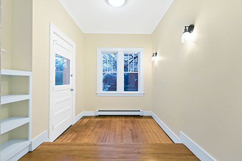 Entryway with wood floors, window, white door, built-in shelves, and wall sconces.