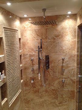 Luxurious tiled shower with multiple sprayers, recessed lighting, and a square showerhead.