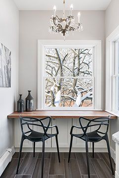 Breakfast nook with a wood countertop, two black chairs, and a window with a snowy view.