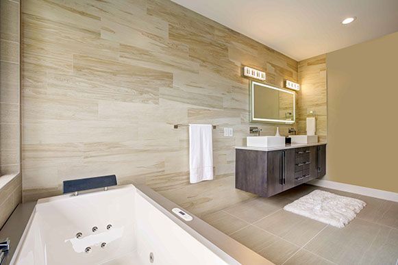 Modern bathroom with a bathtub, floating vanity, and light-colored tile walls.