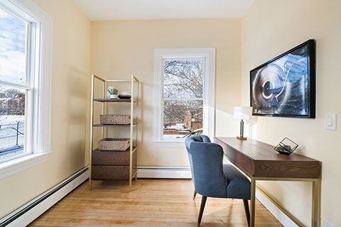 Home office with a desk, chair, shelves, and a window overlooking a snowy landscape.