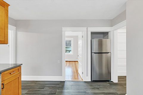 Kitchen interior with gray walls, wood cabinets, and a stainless steel refrigerator.  Hardwood floors are visible.